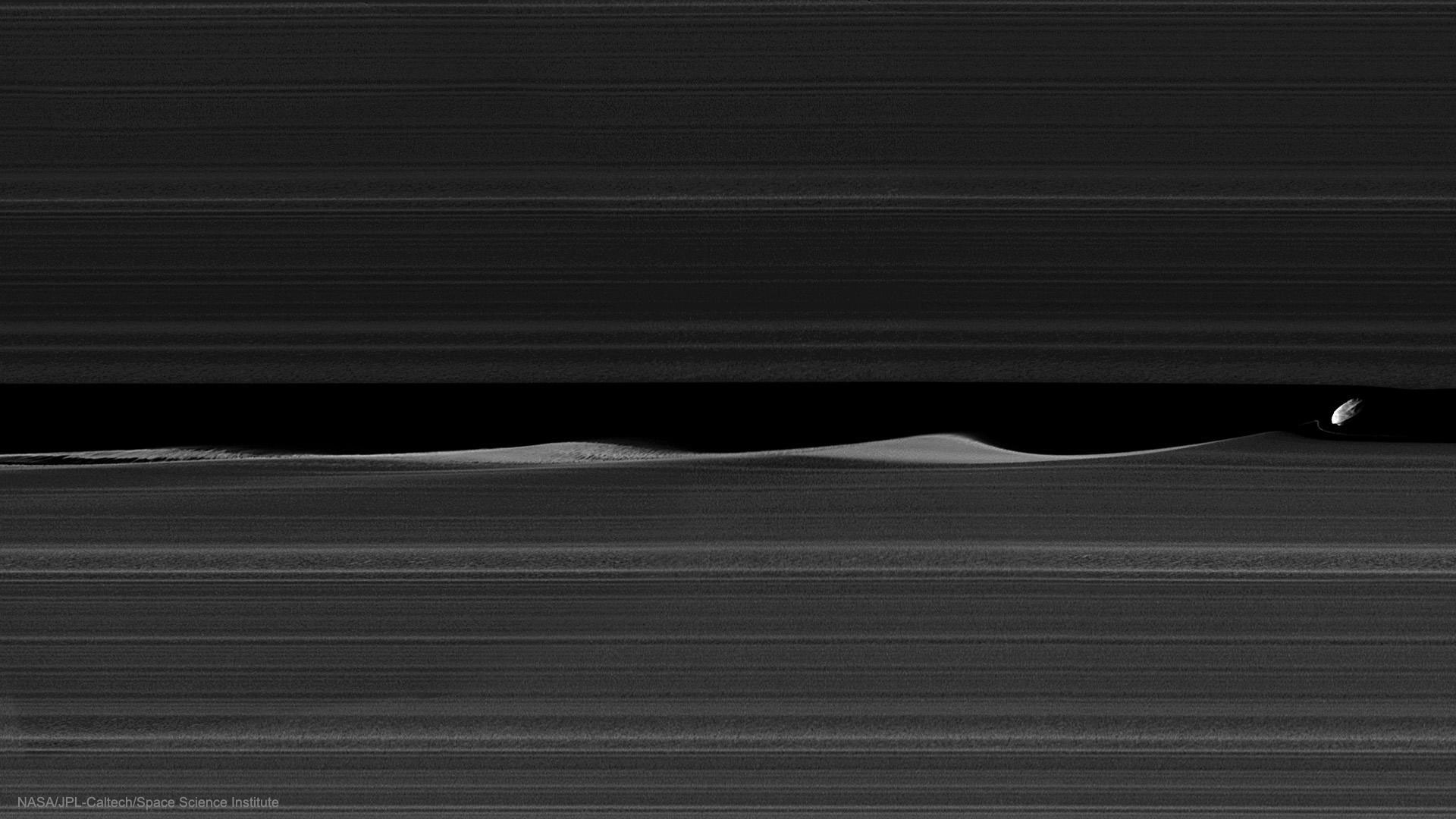 What's happening to the rings of Saturn? Nothing much, just a little moon making waves. The moon is 8-kilometer Daphnis and it is making waves in the Keeler Gap of Saturn's rings using just its gravity -- as it bobs up and down, in and out.  The featured image is a wide-field version of a previously released image taken last month by the robotic Cassini spacecraft during one of its new Grand Finale orbits. Daphnis can be seen on the far right, sporting ridges likely accumulated from ring particles.  Daphnis was discovered in Cassini images in 2005 and raised mounds of ring particles so high in 2009 -- during Saturn's equinox when the ring plane pointed directly at the Sun -- that they cast notable shadows.