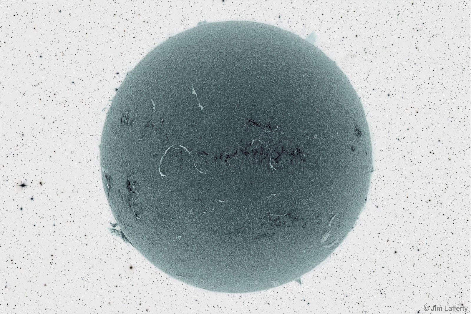 Does this strange dark ball look somehow familiar? If so, that might be because it is our Sun. In the featured image from 2012, a detailed solar view was captured originally in a very specific color of red light, then rendered in black and white, and then color inverted. Once complete, the resulting image was added to a starfield, then also color inverted. Visible in the image of the Sun are long light filaments, dark active regions, prominences peeking around the edge, and a moving carpet of hot gas. The surface of our Sun can be a busy place, in particular during Solar Maximum, the time when its surface magnetic field is wound up the most. Besides an active Sun being so picturesque, the plasma expelled can also become picturesque when it impacts the Earth's magnetosphere and creates auroras.    Follow APOD on: Facebook,  Google Plus,  Instagram, or Twitter