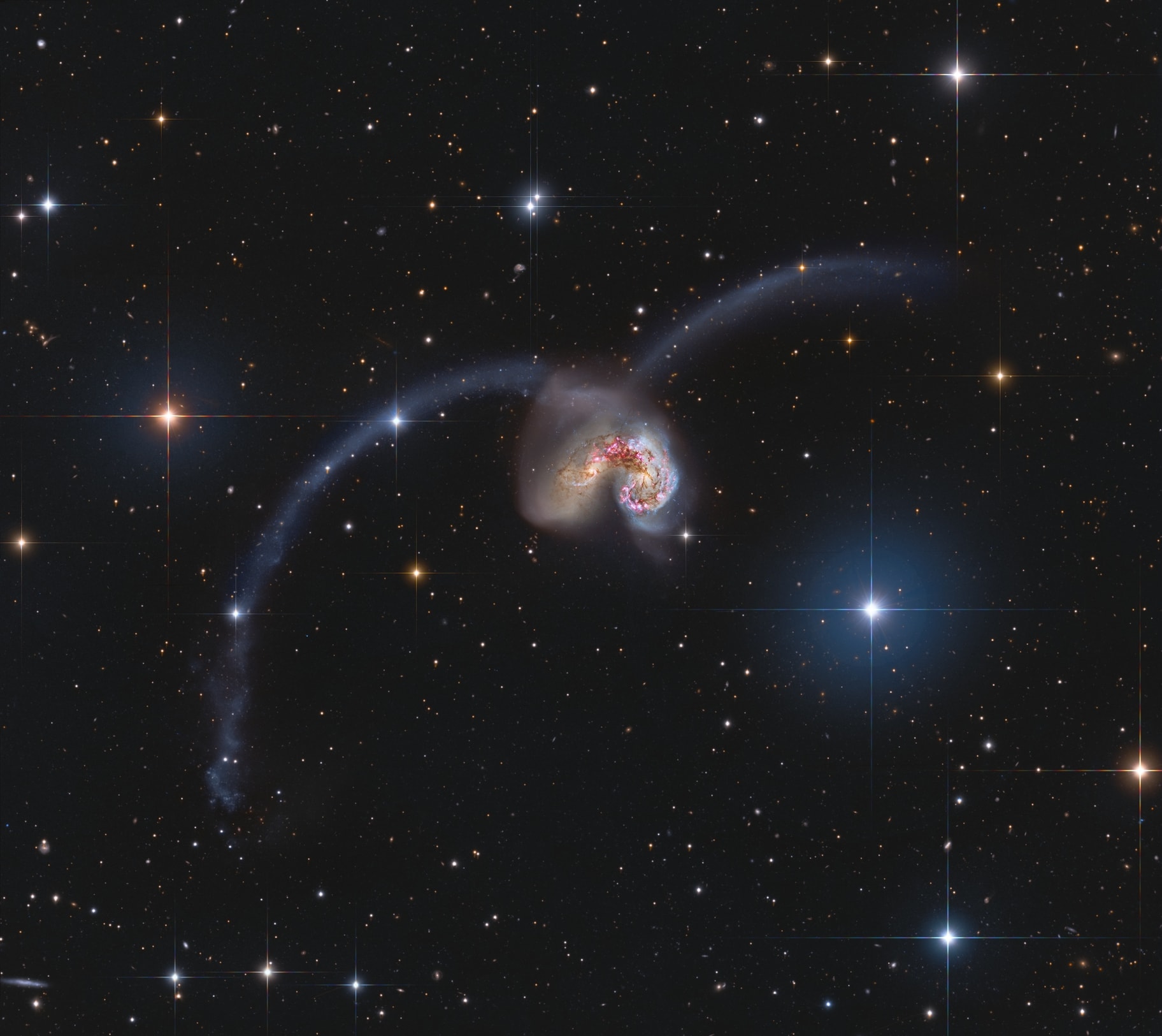 Some 60 million light-years away in the southerly constellation Corvus, two large galaxies are colliding. Stars in the two galaxies, cataloged as NGC 4038 and NGC 4039, very rarely collide in the course of the ponderous cataclysm that lasts for hundreds of millions of years. But the galaxies' large clouds of molecular gas and dust often do, triggering furious episodes of star formation near the center of the cosmic wreckage. Spanning over 500 thousand light-years, this stunning view also reveals new star clusters and matter flung far from the scene of the accident by gravitational tidal forces. The remarkable mosaicked image was constructed using data from the ground-based Subaru telescope to bring out large-scale and faint tidal streams, and Hubble Space Telescope data of extreme detail in the bright cores. The suggestive visual appearance of the extended arcing structures gives the galaxy pair its popular name - The Antennae.