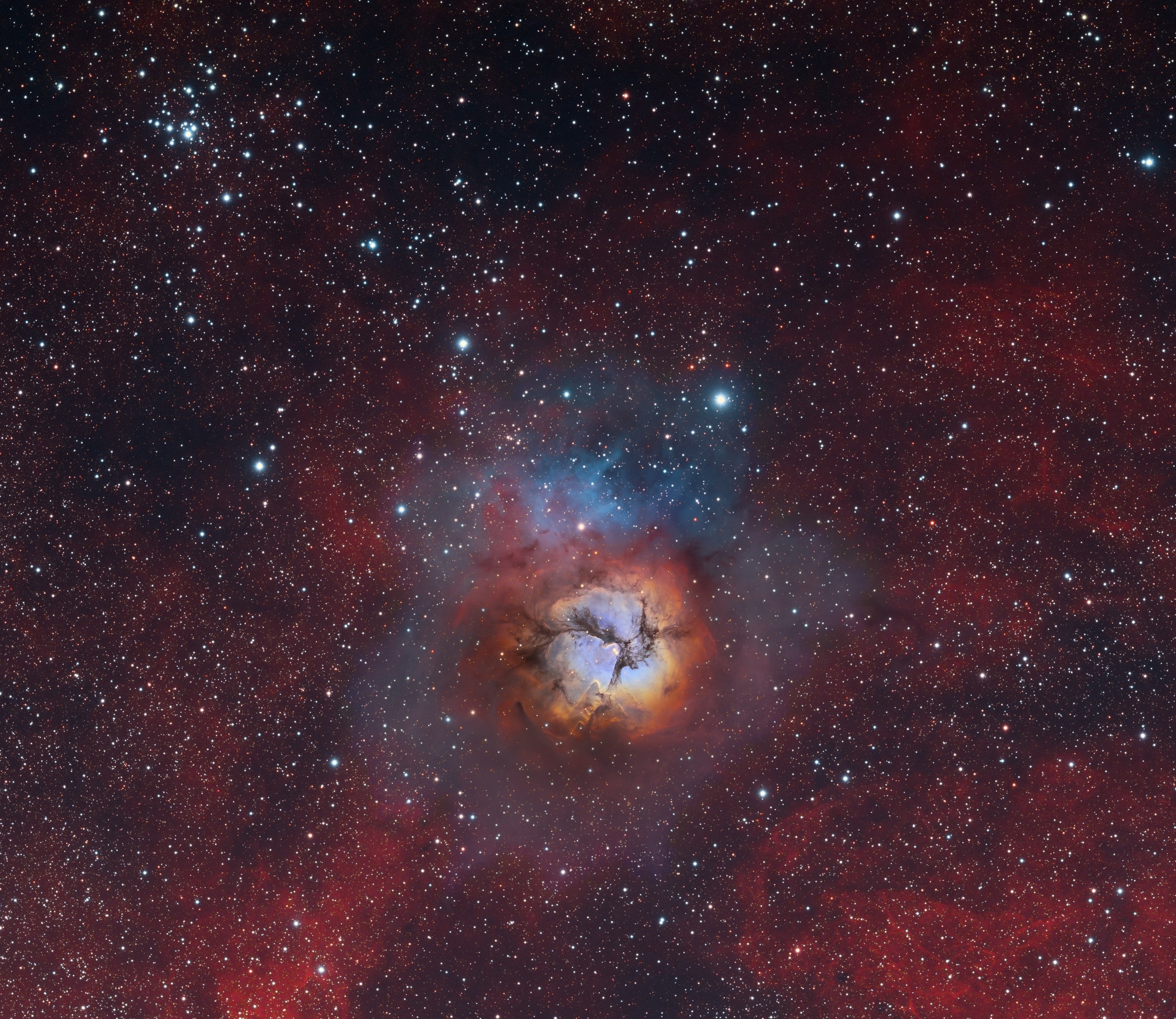 The beautiful Trifid Nebula, also known as Messier 20, lies about 5,000 light-years away, a colorful study in cosmic contrasts. It shares this nearly 1 degree wide field with open star cluster Messier 21 (top left). Trisected by dust lanes the Trifid itself is about 40 light-years across and a mere 300,000 years old. That makes it one of the youngest star forming regions in our sky, with newborn and embryonic stars embedded in its natal dust and gas clouds. Estimates of the distance to open star cluster M21 are similar to M20's, but though they share this gorgeous telescopic skyscape there is no apparent connection between the two. M21's stars are much older, about 8 million years old. M20 and M21 are easy to find with even a small telescope in the nebula rich constellation Sagittarius. In fact, this well-composed scene is a composite from two different telescopes. Using narrowband data it blends a high resolution image of M20 with a wider field image extending to M21.