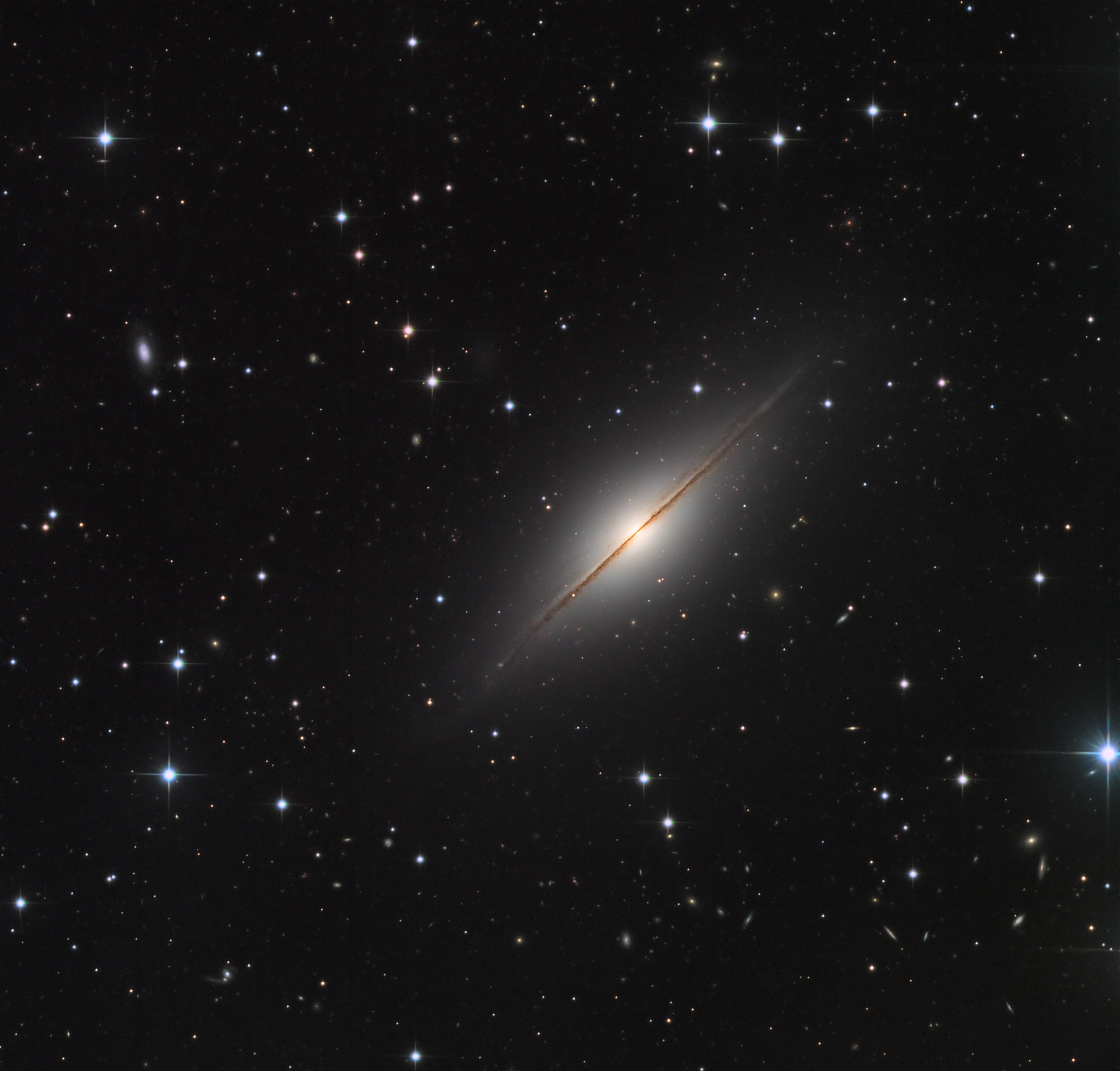 Point your telescope toward the high flying constellation Pegasus and you can find this expanse of Milky Way stars and distant galaxies. Dominated by NGC 7814, the pretty field of view would almost be covered by a full moon. NGC 7814 is sometimes called the Little Sombrero for its resemblance to the brighter more famous M104, the Sombrero Galaxy. Both Sombrero and Little Sombrero are spiral galaxies seen edge-on, and both have extensive halos and central bulges cut by a thin disk with thinner dust lanes in silhouette. In fact, NGC 7814 is some 40 million light-years away and an estimated 60,000 light-years across. That actually makes the Little Sombrero about the same physical size as its better known namesake, appearing smaller and fainter only because it is farther away. Very faint dwarf galaxies, potentially satellites of NGC 7814, have been discovered in deep exposures of the Little Sombrero.