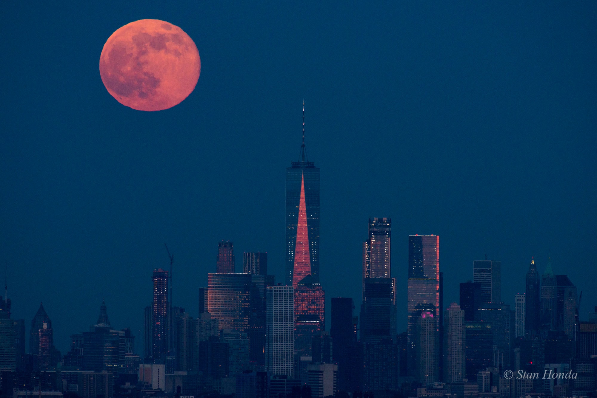 A Full Moon rose as the Sun set on June 9, known to some as a Strawberry Moon. Close to the horizon and taking on the warm color of reflected sunlight filtered through a dense and dusty atmosphere, the fully illuminated lunar disk poses with the skyscrapers along the southern Manhattan skyline in this telephoto snapshot. The picture was taken from Eagle Rock Reservation, a park in West Orange, New Jersey, planet Earth. That's about 13 miles from southern Manhattan and some 240,000 miles from the Moon. Foreground faces of the modern towers of steel and glass share the Moon's warm color by reflecting the last rays of the setting Sun. The tallest, with the shining triangular facet, is New York City's One World Trade Center.
