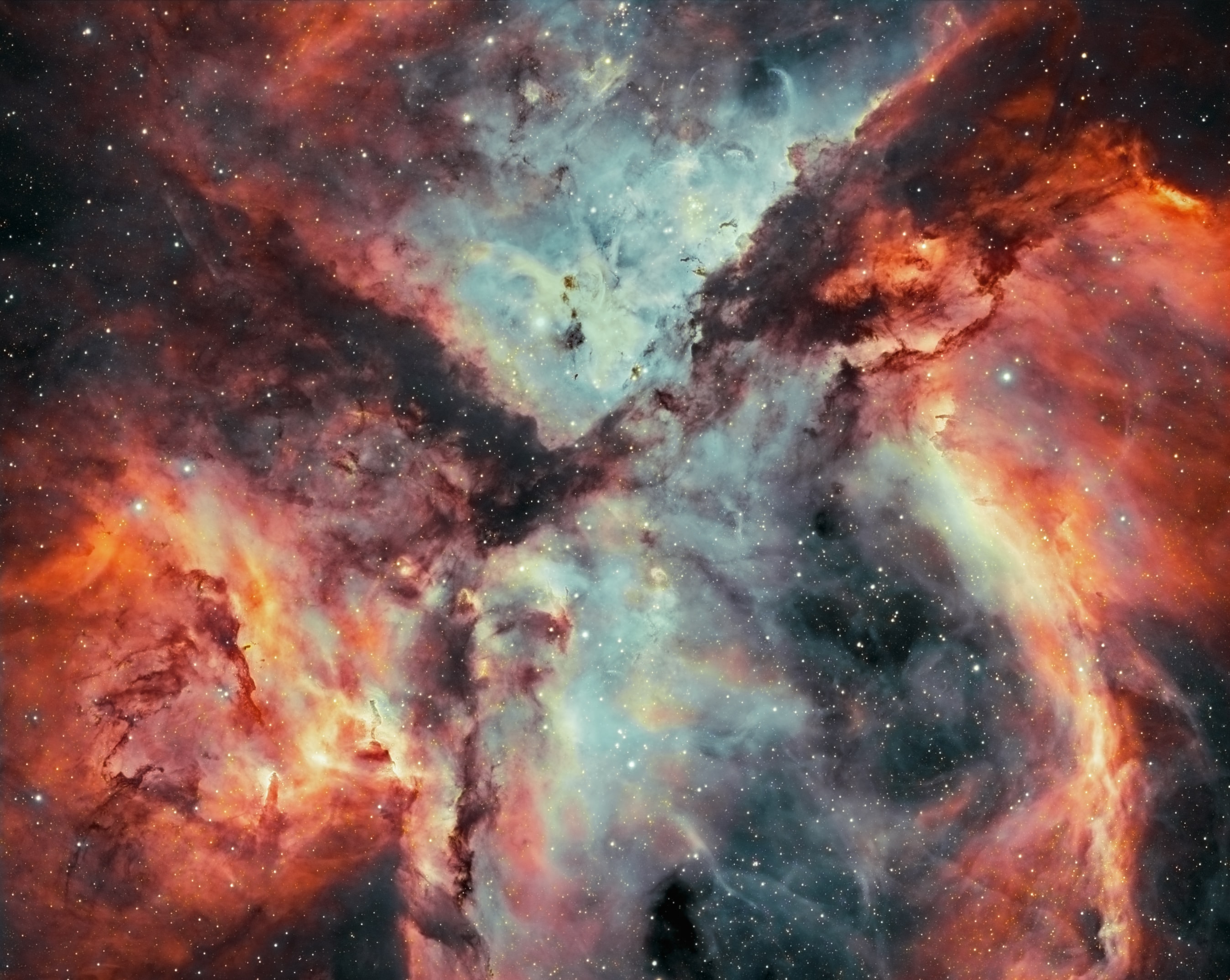 Chaos reigns in the Carina Nebula where massive stars form and die. Striking and detailed, this close-up of a portion of the famous nebula is a combination of light emitted by hydrogen (shown in red) and oxygen (shown in blue).  Dramatic dark dust knots and complex features revealed are sculpted by the winds and radiation of Carina's massive and energetic stars.  One iconic feature of the Carina Nebula is the dark V-shaped dust lane that occurs in the top half of the image. The Carina Nebula spans about 200 light years, lies about 7,500 light years distant, and is visible with binoculars toward the southern constellation of Carina. In a billion years after the dust settles -- or is destroyed, and the gas dissipates -- or gravitationally condenses, then only the stars will remain -- but not even the brightest ones.