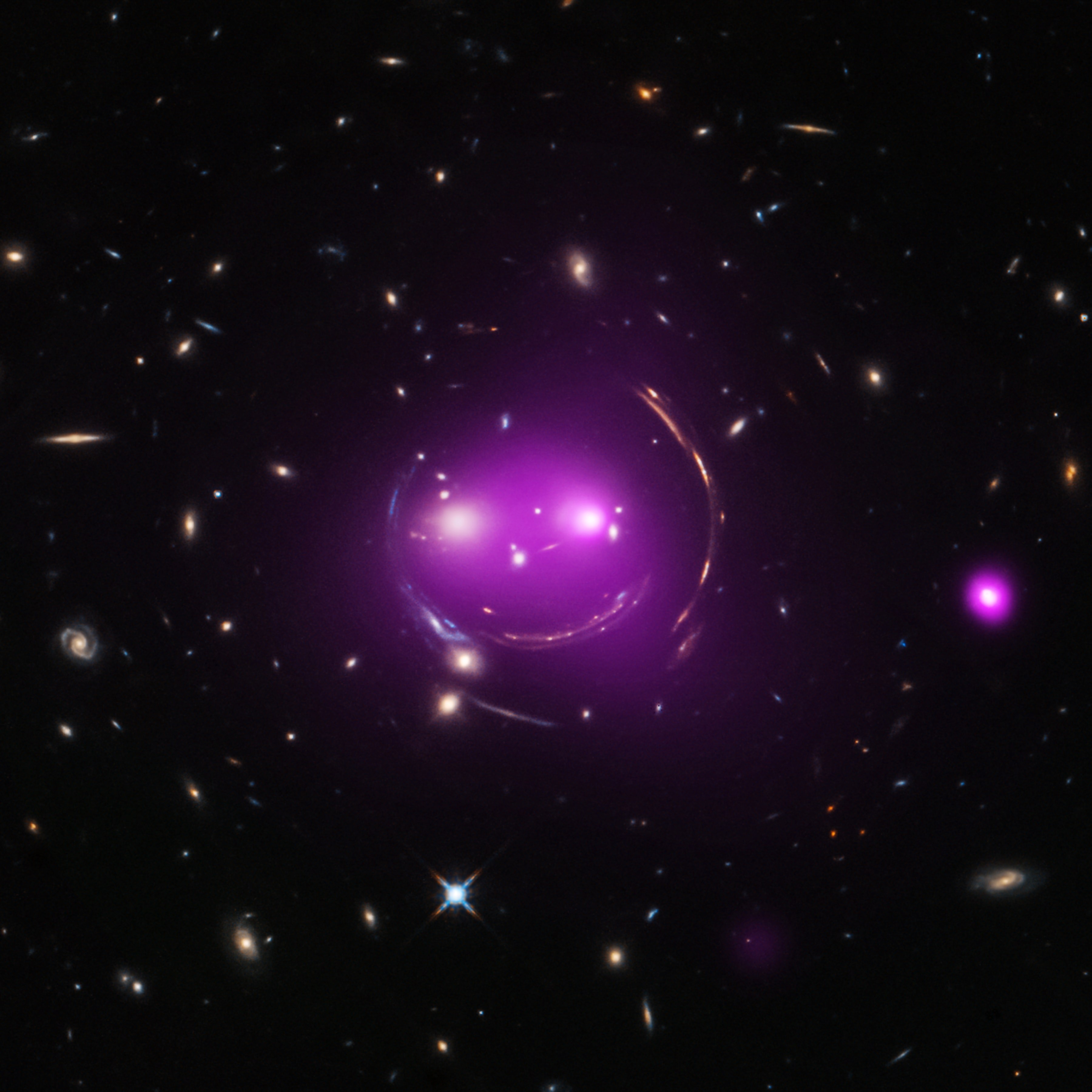 Albert Einstein's general theory of relativity, published over 100 years ago, predicted the phenomenon of gravitational lensing. And that's what gives these distant galaxies such a whimsical appearance, seen through the looking glass of X-ray and optical image data from the Chandra and Hubble space telescopes. Nicknamed the Cheshire Cat galaxy group, the group's two large elliptical galaxies are suggestively framed by arcs. The arcs are optical images of distant background galaxies lensed by the foreground group's total distribution of gravitational mass. Of course, that gravitational mass is dominated by dark matter. The two large elliptical "eye" galaxies represent the brightest members of their own galaxy groups which are merging. Their relative collisional speed of nearly 1,350 kilometers/second heats gas to millions of degrees producing the X-ray glow shown in purple hues. Curiouser about galaxy group mergers? The Cheshire Cat group grins in the constellation Ursa Major, some 4.6 billion light-years away.