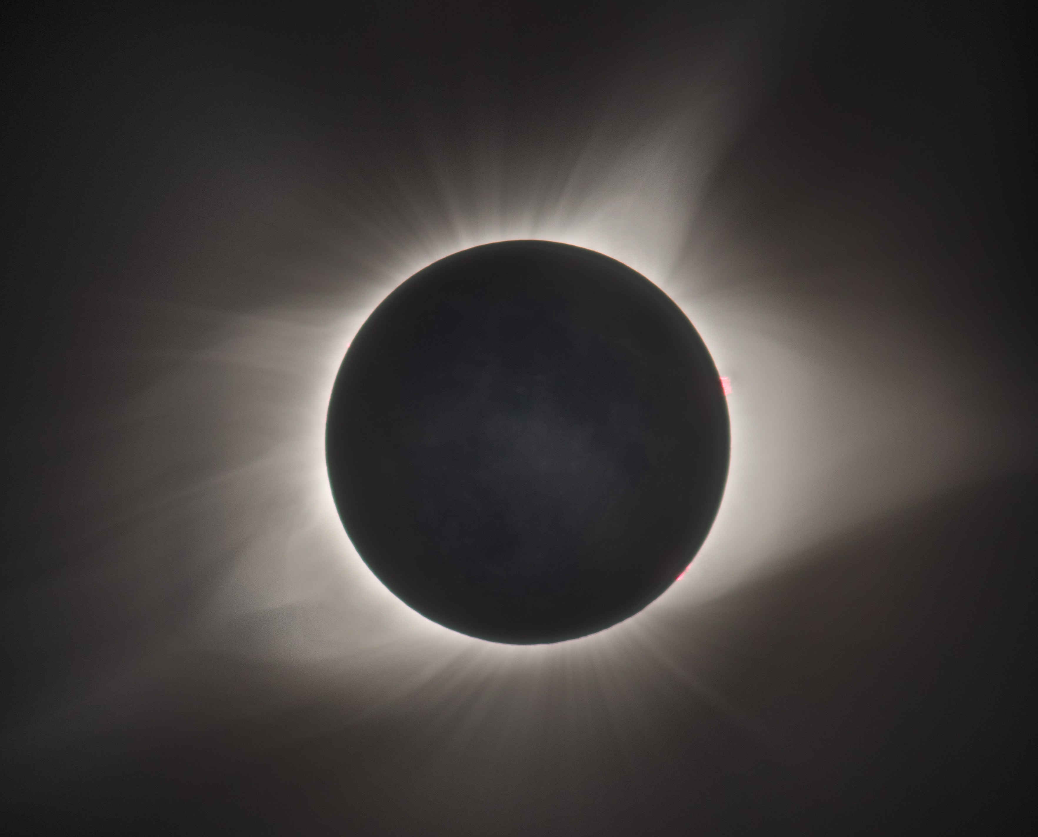 During a total solar eclipse, the Sun's extensive outer atmosphere, or corona, is an inspirational sight. Streamers and shimmering features visible to the eye span a brightness range of over 10,000 to 1, making them notoriously difficult to capture in a single photograph. But this composite of telescopic images covers a wide range of exposure times to reveal the crown of the Sun in all its glory. The aligned and stacked digital frames were taken in clear skies above Stanley, Idaho in the Sawtooth Mountains during the Sun's total eclipse on August 21. A pinkish solar prominence extends just beyond the right edge of the solar disk. Even small details on the dark night side of the New Moon can be made out, illuminated by sunlight reflected from a Full Earth.