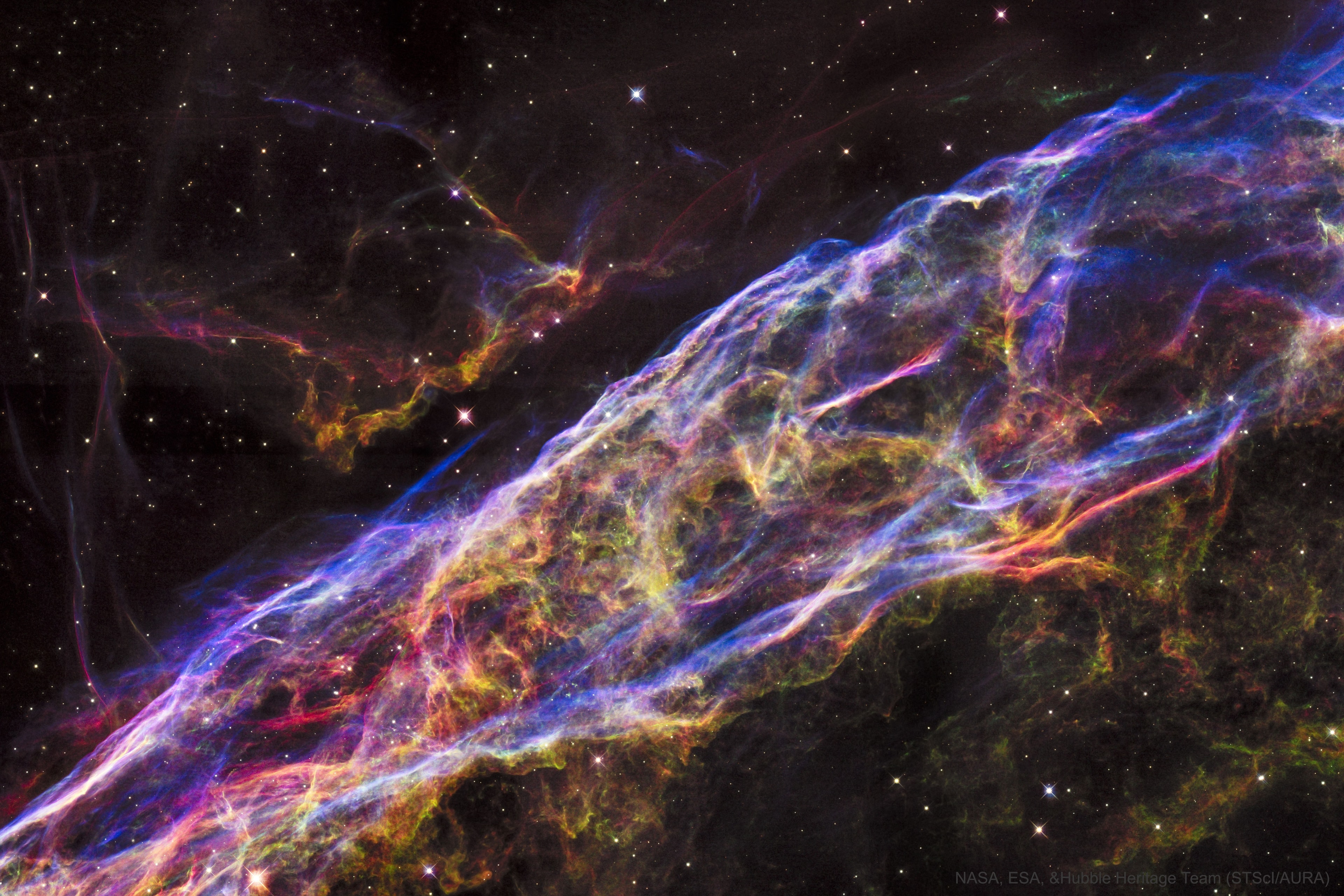 Wisps like this are all that remain visible of a Milky Way star.  About 7,000 years ago that star exploded in a supernova leaving the Veil Nebula. At the time, the expanding cloud was likely as bright as a crescent Moon, remaining visible for weeks to people living at the dawn of recorded history.  Today, the resulting supernova remnant, also known as the Cygnus Loop, has faded and is now visible only through a small telescope directed toward the constellation of the Swan (Cygnus). The remaining Veil Nebula is physically huge, however, and even though it lies about 1,400 light-years distant, it covers over five times the size of the full Moon.  The featured picture is a Hubble Space Telescope mosaic of six images together covering a span of only about two light years, a small part of the expansive supernova remnant. In images of the complete Veil Nebula, even studious readers might not be able to identify the featured filaments.