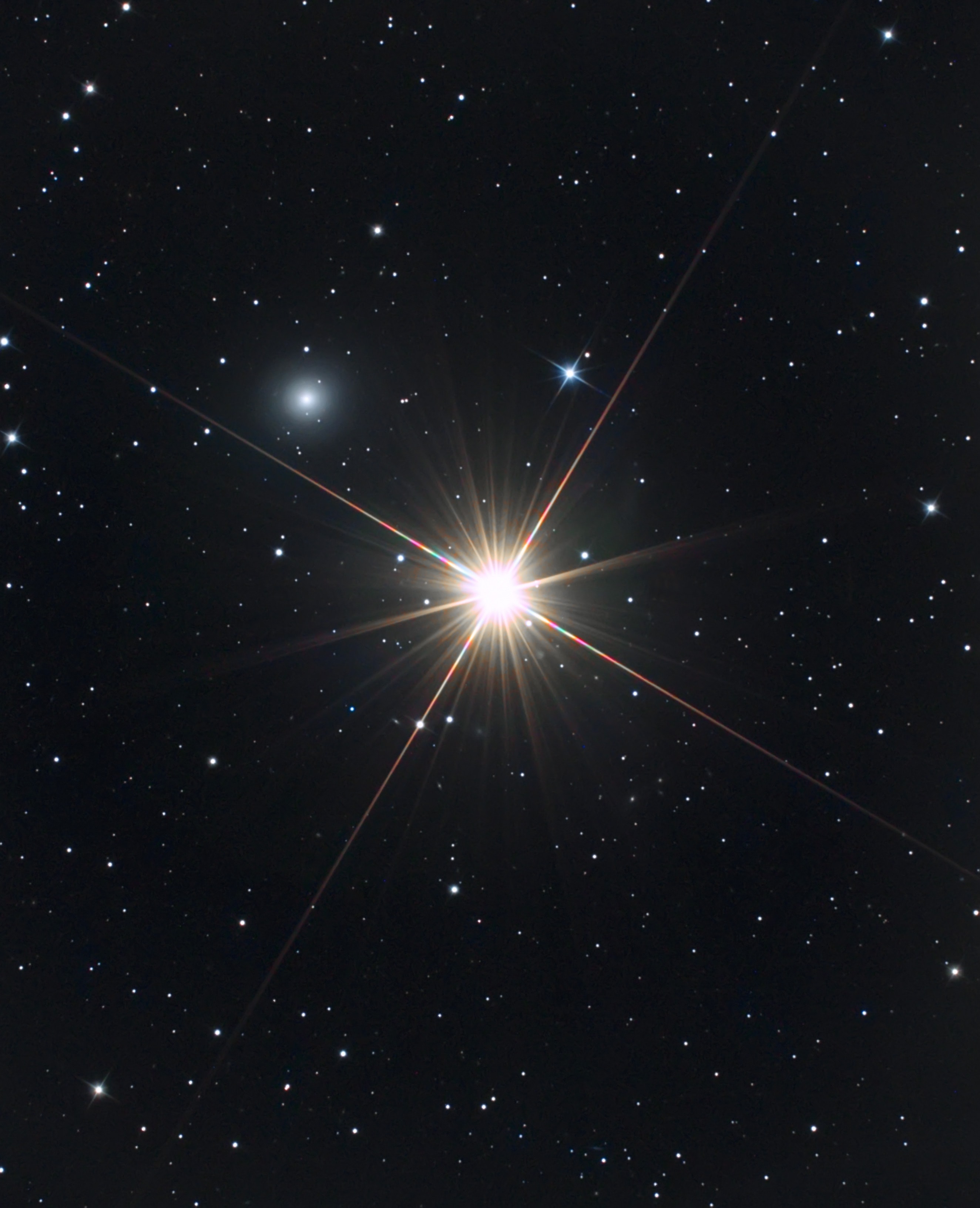 As far as ghosts go, Mirach's Ghost isn't really that scary. Mirach's Ghost is just a faint, fuzzy galaxy, well known to astronomers, that happens to be seen nearly along the line-of-sight to Mirach, a bright star. Centered in this star field, Mirach is also called Beta Andromedae. About 200 light-years distant, Mirach is a red giant star, cooler than the Sun but much larger and so intrinsically much brighter than our parent star. In most telescopic views, glare and diffraction spikes tend to hide things that lie near Mirach and make the faint, fuzzy galaxy look like a ghostly internal reflection of the almost overwhelming starlight. Still, appearing in this sharp image just above and to the left of Mirach, Mirach's Ghost is cataloged as galaxy NGC 404 and is estimated to be some 10 million light-years away.