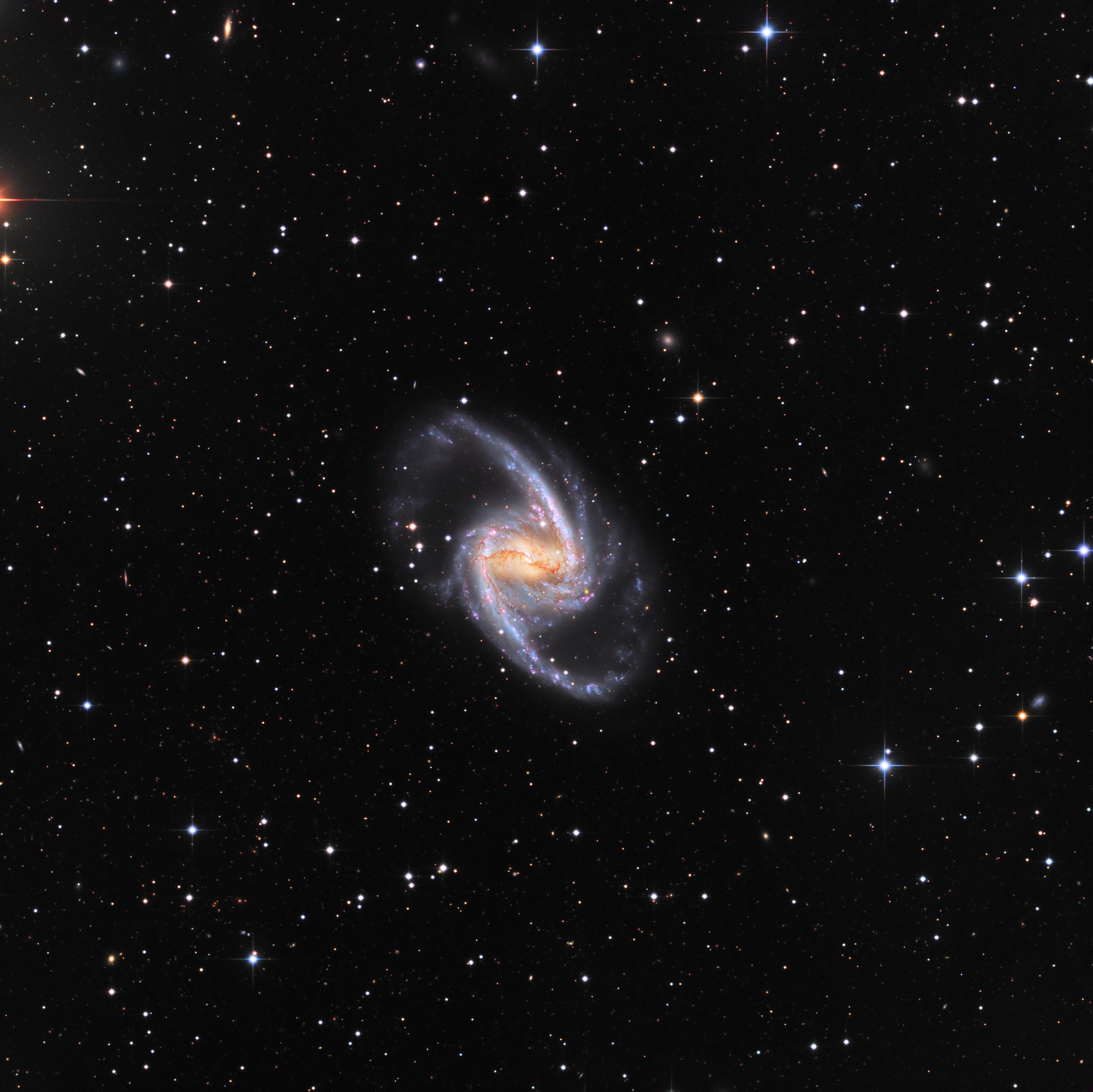 Barred spiral galaxy NGC 1365 is truly a majestic island universe some 200,000 light-years across. Located a mere 60 million light-years away toward the chemical constellation Fornax, NGC 1365 is a dominant member of the well-studied Fornax galaxy cluster. This impressively sharp color image shows intense star forming regions at the ends of the bar and along the spiral arms, and details of dust lanes cutting across the galaxy's bright core. At the core lies a supermassive black hole. Astronomers think NGC 1365's prominent bar plays a crucial role in the galaxy's evolution, drawing gas and dust into a star-forming maelstrom and ultimately feeding material into the central black hole.