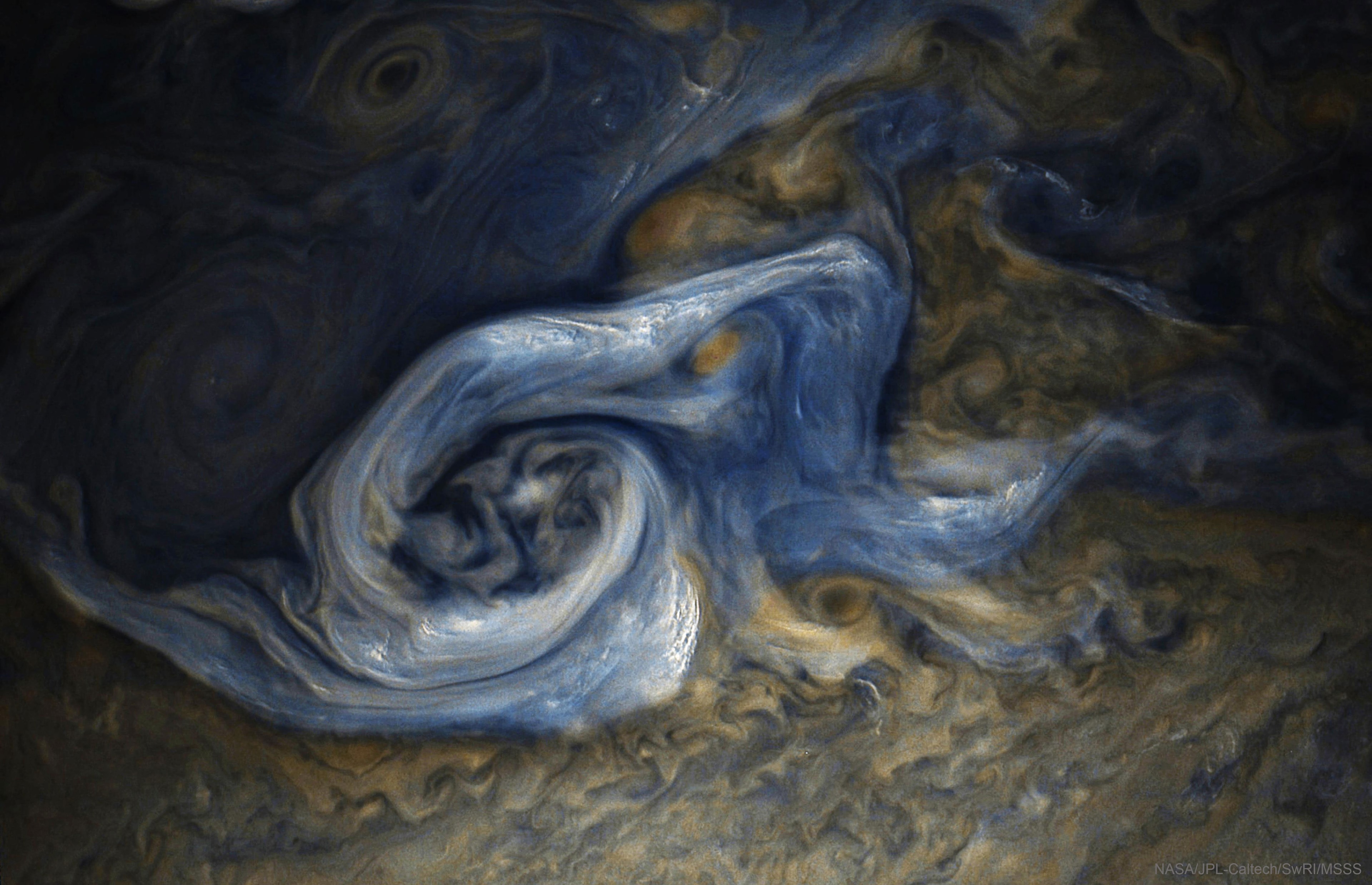 Some storms on Jupiter are quite complex. The swirling storm was captured late last month by the NASA's robotic Juno spacecraft currently orbiting the Solar System's largest planet.  The featured image spans about 30,000 kilometers, making this storm system just about as wide as planet Earth.  The disturbance rotates counter-clockwise and shows a cloud pattern that includes light-colored updrafts thought to be composed predominantly of ammonia ice.  These light clouds are the highest up and even cast discernable shadows toward the right.  Juno will continue to orbit and probe Jupiter over the next few years as it tries to return data that help us to better understand Jupiter's atmospheric water abundance and if the planet has a solid surface underneath these fascinating clouds.