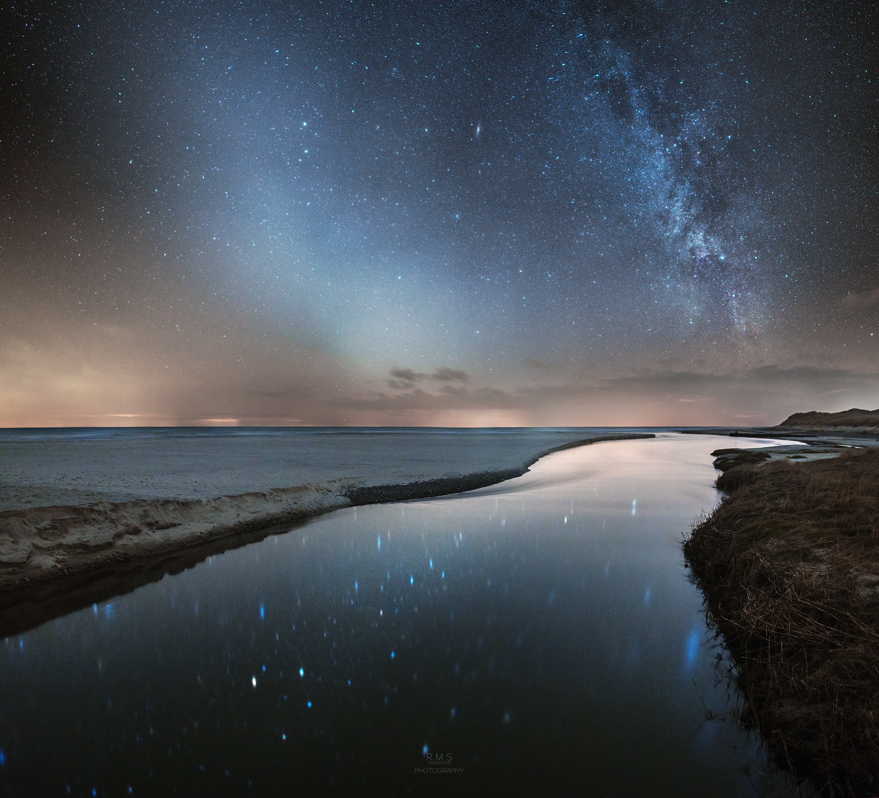 What are these two bands in the sky? The more commonly seen band is the one on the right and is the central band of our Milky Way galaxy. Our Sun orbits in the disk of this spiral galaxy, so that from inside, this disk appears as a band of comparable brightness all the way around the sky. The Milky Way band can also be seen all year -- if out away from city lights.  The less commonly seem band, on the left, is zodiacal light -- sunlight reflected from dust orbiting the Sun in our Solar System.  Zodiacal light is brightest near the Sun and so is best seen just before sunrise or just after sunset.  On some evenings in the north, particularly during the months of March and April, this ribbon of zodiacal light can appear quite prominent after sunset.  It has recently been determined that zodiacal dust was mostly expelled by comets that have passed near Jupiter.  Only on certain times of the year will the two bands be seen side by side, in parts of the sky, like this.  Here the two streaks of light appear like the continuation of the banks of the Liver River into the sky. The featured panorama of consecutive exposures was recorded about three weeks ago in North Jutland,  Denmark.