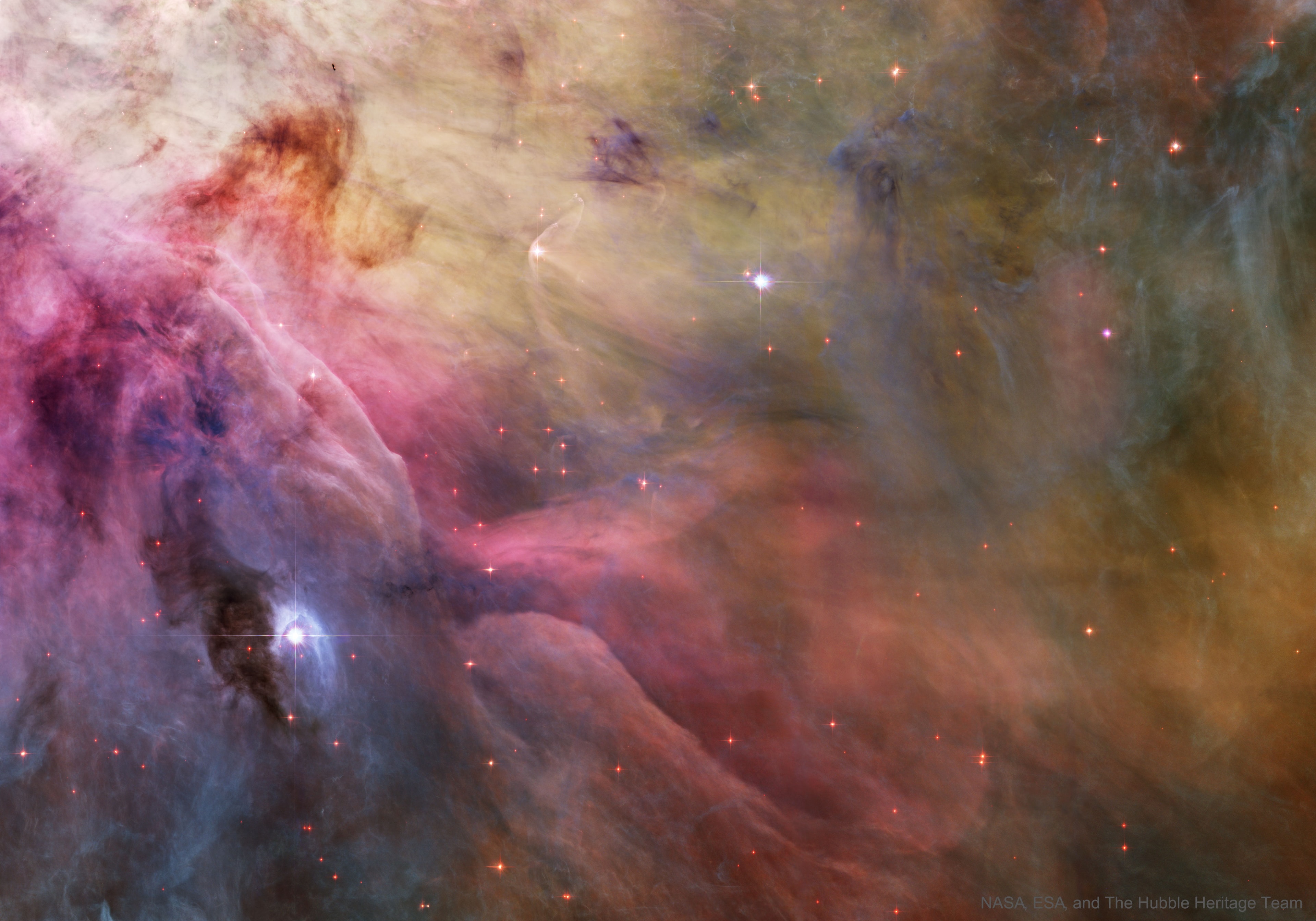Stars can make waves in the Orion Nebula's sea of gas and dust.  This esthetic close-up of cosmic clouds and stellar winds features LL Orionis, interacting with the Orion Nebula flow. Adrift in Orion's stellar nursery and still in its formative years, variable star LL Orionis produces a wind more energetic than the wind from our own middle-aged Sun. As the fast stellar wind runs into slow moving gas a shock front is formed, analogous to the bow wave of a boat moving through water or a plane traveling at supersonic speed. The small, arcing, graceful structure just above and left of center is LL Ori's cosmic bow shock, measuring about half a light-year across. The slower gas is flowing away from the Orion Nebula's hot central star cluster, the Trapezium, located off the upper left corner of the picture. In three dimensions, LL Ori's wrap-around shock front is shaped like a bowl that appears brightest when viewed along the "bottom" edge. This beautiful painting-like photograph is part of a large mosaic view of the complex stellar nursery in Orion, filled with a myriad of fluid shapes associated with star formation.