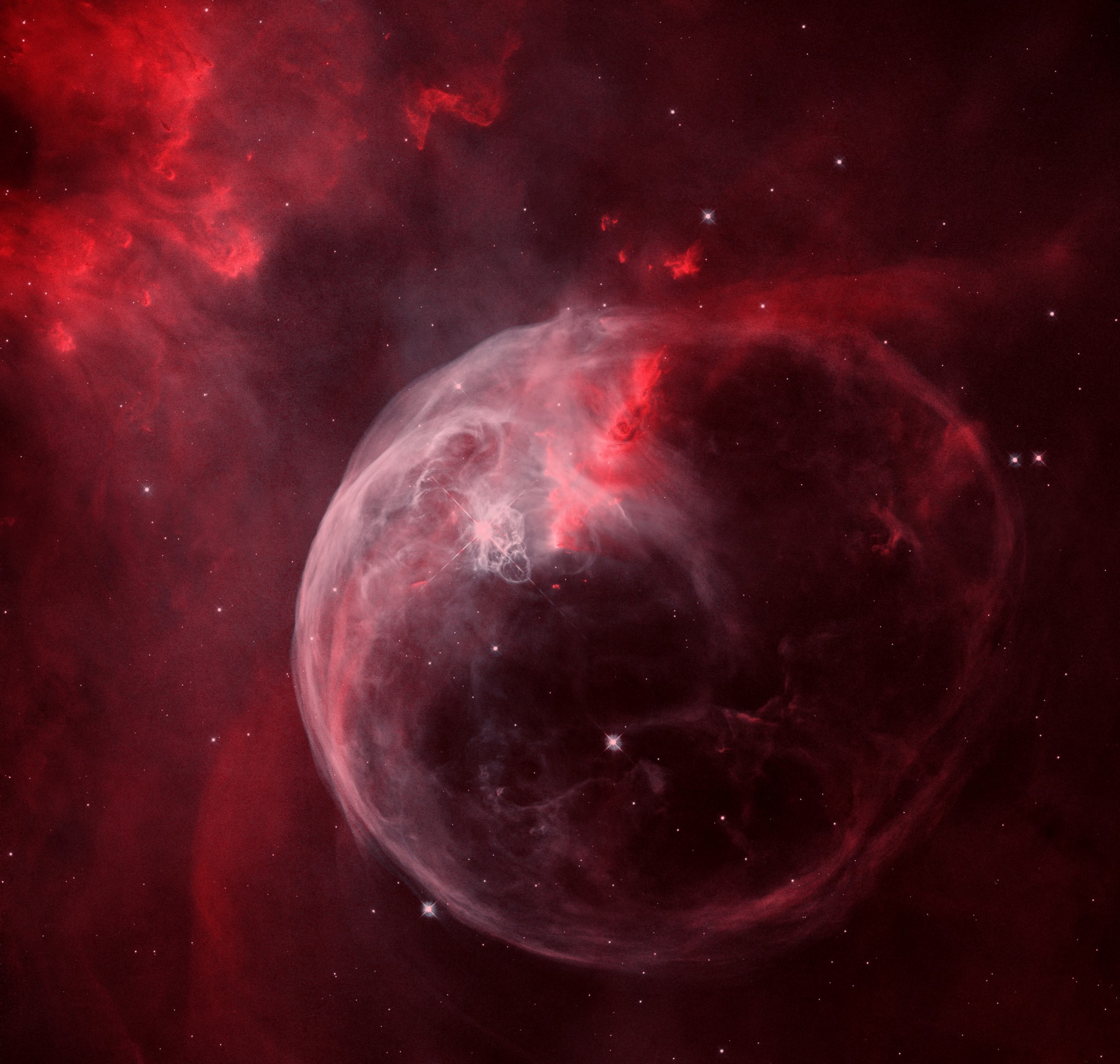 Blown by the wind from a massive star, this interstellar apparition has a surprisingly familiar shape. Cataloged as NGC 7635, it is also known simply as The Bubble Nebula. Although it looks delicate, the 7 light-year diameter bubble offers evidence of violent processes at work. Above and left of the Bubble's center is a hot, O-type star, several hundred thousand times more luminous and some 45 times more massive than the Sun. A fierce stellar wind and intense radiation from that star has blasted out the structure of glowing gas against denser material in a surrounding molecular cloud. The intriguing Bubble Nebula and associated cloud complex lie a mere 7,100 light-years away toward the boastful constellation Cassiopeia. This sharp, tantalizing view of the cosmic bubble is a composite of Hubble Space Telescope image data from 2016, reprocessed to present the nebula's intense narrowband emission in an approximate true color scheme.