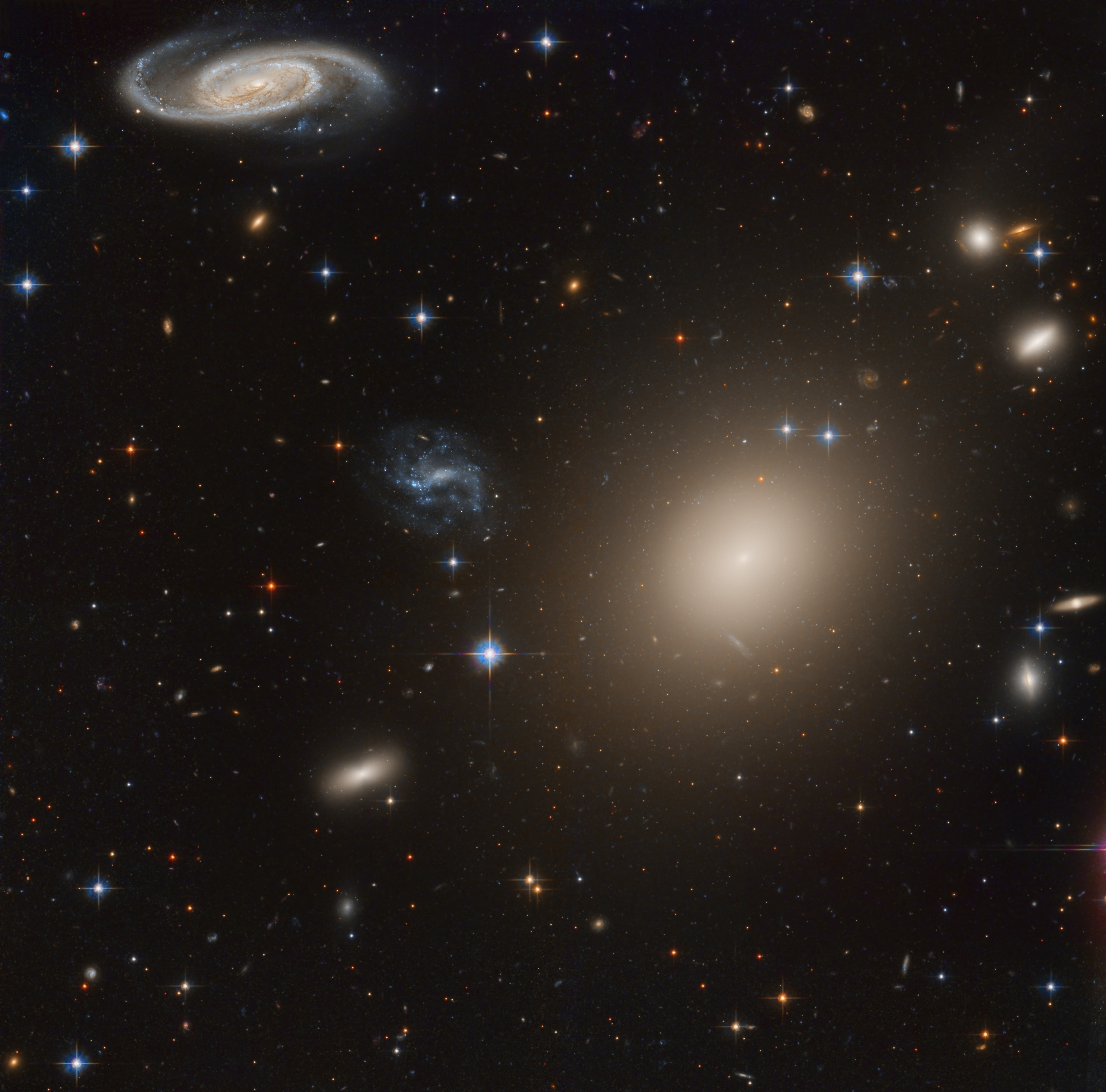 This stunning group of galaxies is far, far away, about 450 million light-years from planet Earth and cataloged as galaxy cluster Abell S0740. Dominated by the cluster's large central elliptical galaxy (ESO 325-G004), this reprocessed Hubble Space Telescope view takes in a remarkable assortment of galaxy shapes and sizes with only a few spiky foreground stars scattered through the field. The giant elliptical galaxy (right of center) spans over 100,000 light years and contains about 100 billion stars, comparable in size to our own spiral Milky Way galaxy. The Hubble data can reveal a wealth of detail in even these distant galaxies, including arms and dust lanes, star clusters, ring structures, and gravitational lensing arcs.