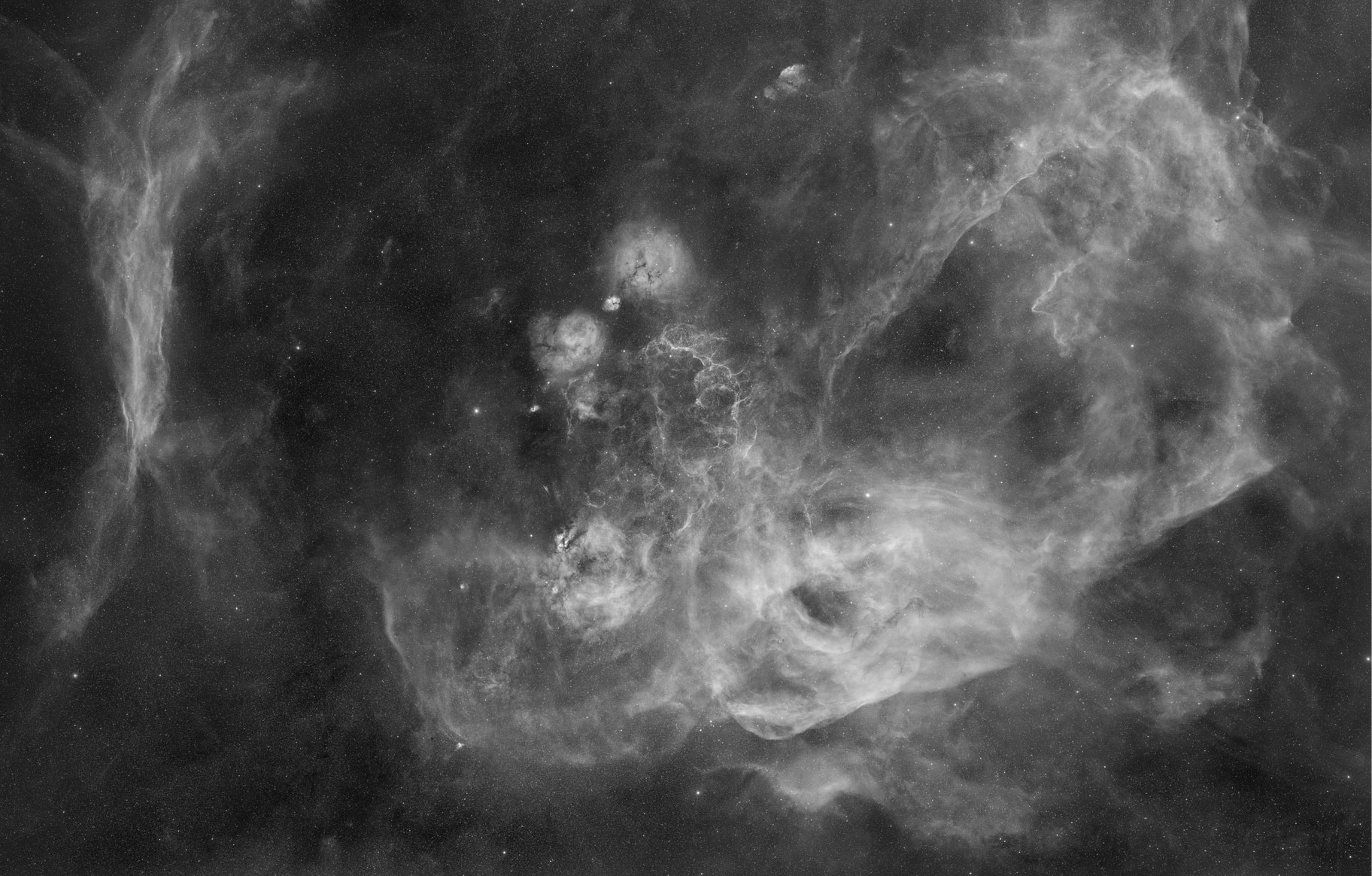 Named for a cosmic cloud hunter, Australian astronomer Colin Stanley Gum (1924-1960), The Gum Nebula is so large and close it is actually hard to see. In fact, we are only about 450 light-years from the front edge and 1,500 light-years from the back edge of this interstellar expanse of glowing hydrogen gas. Covered in this 40+ degree-wide monochrome mosaic of Hydrogen-alpha images, the faint emission region stands out against the background of Milky Way stars. The complex nebula is thought to be a supernova remnant over a million years old, sprawling across the Ship's southern constellations Vela and Puppis. This spectacular wide field view also explores many objects embedded in The Gum Nebula, including the younger Vela supernova remnant.