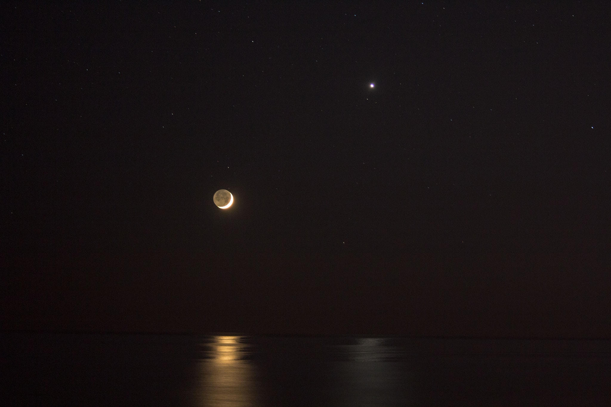 Posing near the western horizon, a brilliant evening star and slender young crescent shared reflections in a calm sea last Thursday after sunset. Recorded in this snapshot from a beach at Santa Marinella near Rome, Italy, the lovely celestial conjunction of the two brightest beacons in the night sky could be enjoyed around the world. Seaside, light reflected by briefly horizontal surfaces of the gentle waves forms the shimmering columns across the water. Similar reflections by fluttering atmospheric ice crystals can create sometimes mysterious pillars of light. Of course, earthlight itself visibly illuminates the faint lunar night side.