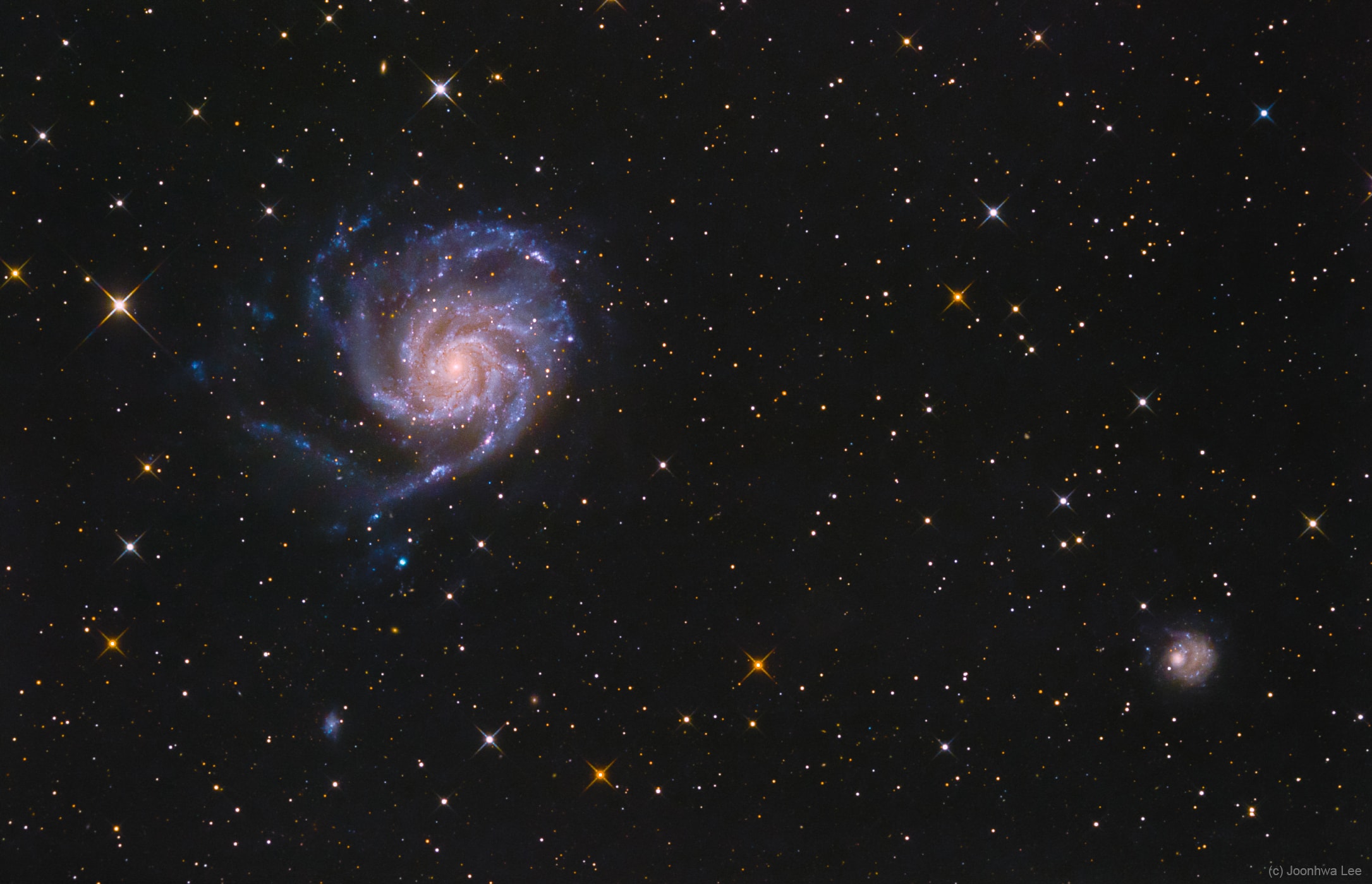 Big, beautiful spiral galaxy M101 is one of the last entries in Charles Messier's famous catalog, but definitely not one of the least. About 170,000 light-years across, this galaxy is enormous, almost twice the size of our own Milky Way galaxy. M101 was also one of the original spiral nebulae observed by Lord Rosse's large 19th century telescope, the Leviathan of Parsontown. M101 shares this modern telescopic field of view with spiky foreground stars within the Milky Way and a companion dwarf galaxy NGC 5474 (lower right). The colors of the Milky Way stars can also be found in the starlight from the large island universe. Its core is dominated by light from cool yellowish stars. Along its grand design spiral arms are the blue colors of hotter, young stars mixed with obscuring dust lanes and pinkish star forming regions. Also known as the Pinwheel Galaxy, M101 lies within the boundaries of the northern constellation Ursa Major, about 23 million light-years away. NGC 5474 has likely been distorted by its past gravitational interactions with the dominant M101.