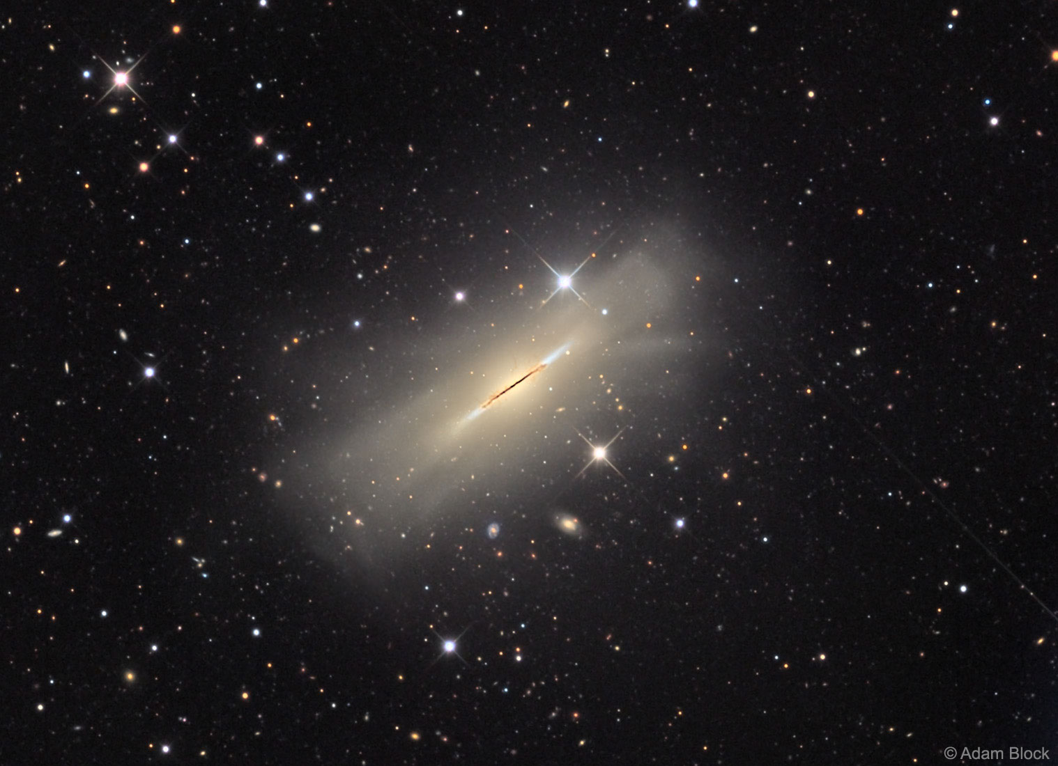 What kind of celestial object is this? A relatively normal galaxy -- but seen from its edge.  Many disk galaxies are actually just as thin as NGC 5866, pictured here, but are not seen edge-on from our vantage point.  A perhaps more familiar galaxy seen edge-on is our own Milky Way Galaxy.  Cataloged as M102 and NGC 5866, the Spindle galaxy has numerous and complex dust lanes appearing dark and red, while many of the bright stars in the disk give it a more blue underlying hue.  The blue disk of young stars can be seen extending past the dust in the extremely thin galactic plane. There is evidence that the Spindle galaxy has cannibalized smaller galaxies over the past billion years or so, including multiple streams of faint stars, dark dust that extends away from the main galactic plane, and a surrounding group of galaxies (not shown).  In general, many disk galaxies become thin because the gas that forms them collides with itself as it rotates about the gravitational center. The Spindle galaxy lies about 50 million light years distant toward the constellation of the Dragon (Draco).