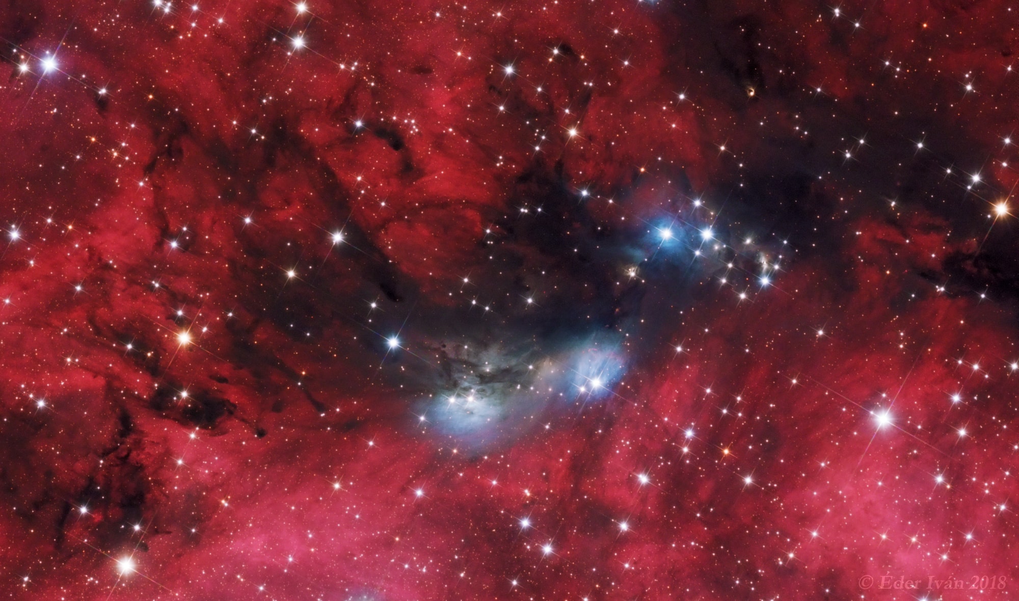 A study in contrasts, this colorful skyscape features stars, dust, and glowing gas in the vicinity of NGC 6914. The complex of reflection nebulae lies some 6,000 light-years away, toward the high-flying northern constellation Cygnus and the plane of our Milky Way Galaxy. Obscuring interstellar dust clouds appear in silhouette while reddish hydrogen emission nebulae, along with the dusty blue reflection nebulae, fill the cosmic canvas. Ultraviolet radiation from the massive, hot, young stars of the extensive Cygnus OB2 association ionize the region's atomic hydrogen gas, producing the characteristic red glow as protons and electrons recombine. Embedded Cygnus OB2 stars also provide the blue starlight strongly reflected by the dust clouds. The nearly 1 degree wide telescopic field of view spans about 100 light-years at the estimated distance of NGC 6914.