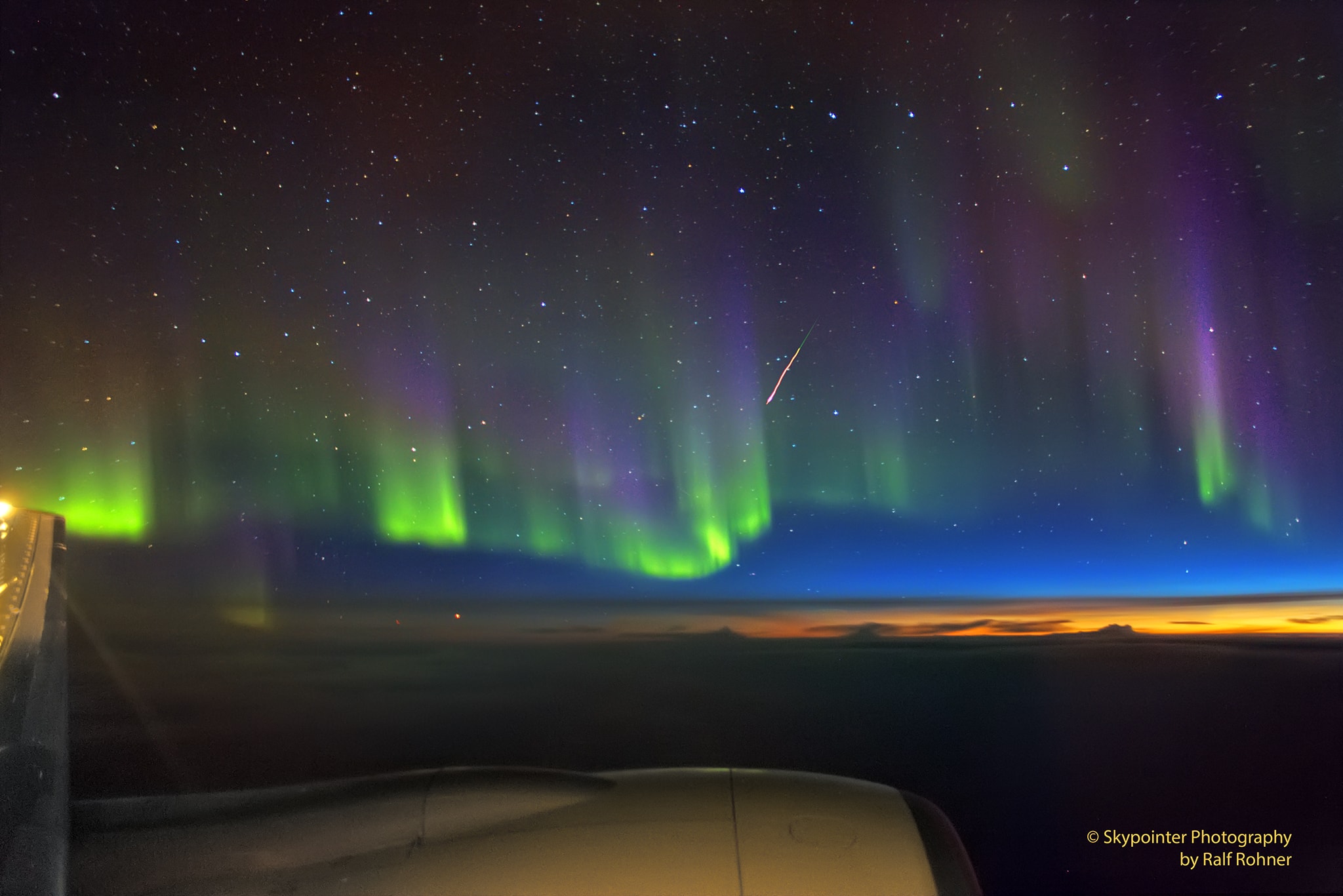 On the August 18 night flight from San Francisco to Zurich, a window seat offered this tantalizing view when curtains of light draped a colorful glow across the sky over Hudson Bay. Constructed by digitally stacking six short exposures made with a hand held camera, the scene records the shimmering aurora borealis or northern lights just as the approaching high altitude sunrise illuminated the northeastern horizon. It also caught the flash of a Perseid meteor streaking beneath the handle stars of the Big Dipper of the north. A few days past the meteor shower's peak, its trail still points across the sky toward Perseus. Beautiful aurorae and shower meteors both occur in Earth's upper atmosphere at altitudes of 100 kilometers or so, far above commercial airline flights. The aurora are caused by energetic charged particles from the magnetosphere, while meteors are trails of comet dust.