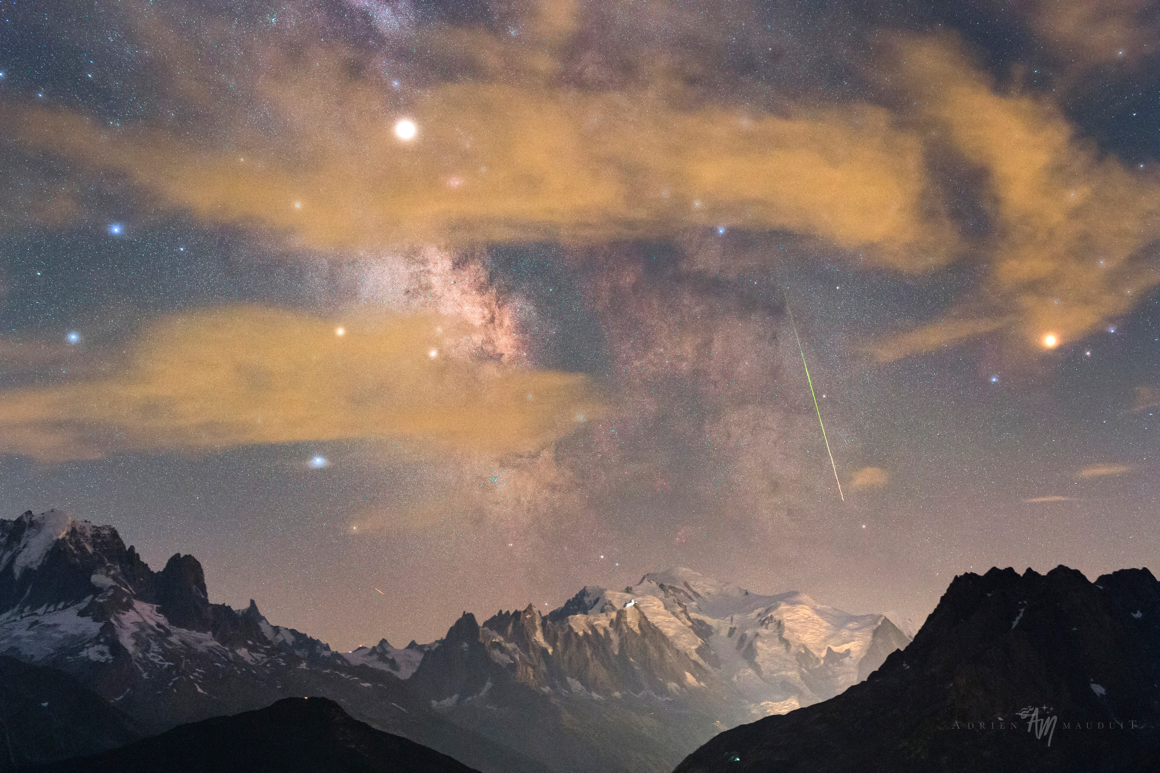 Snowy Mont Blanc is near the center of this atmospheric night skyscape. But high, thin clouds fogged the skies at the photographer's location, looking south toward Europe's highest peak from the southern Swiss Alps. Still, the 13 second exposure finds the faint star fields and dark rifts of the Milky Way above the famous white mountain. Bloated by the mist, bright planet Saturn and Antares (right), alpha star of Scorpius, shine through the clouds to flank the galaxy's central bulge. The high-altitude scene is from the rewarding night of August 12/13, so it also includes the green trail of a Perseid meteor shooting along the galactic plane.