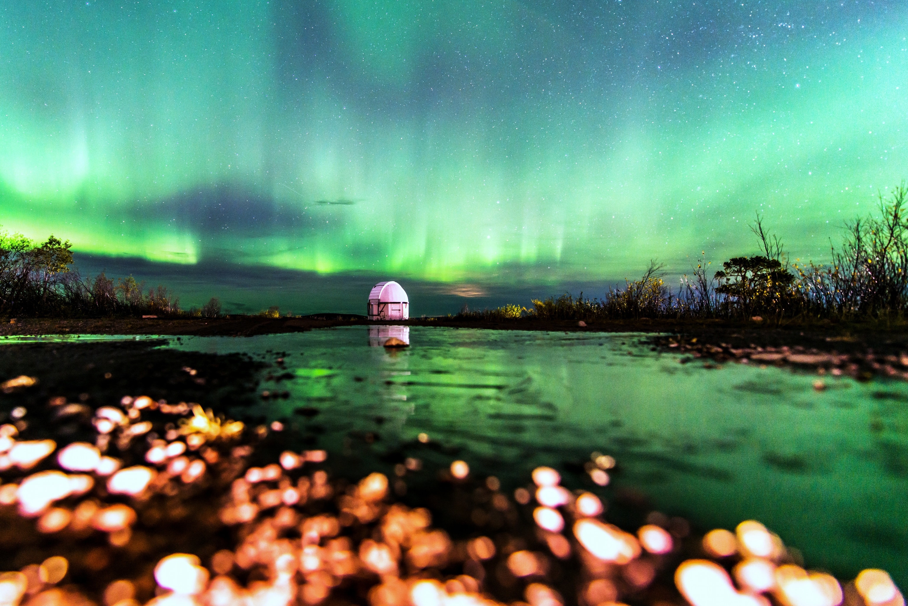 What does an aurora look like to a frog? "Awesome!" is the likely answer, suggested by this imaginative snapshot taken on October 3rd from Kiruna, Sweden. Frequented by apparitions of the northern lights, Kiruna is located in Lapland north of the Arctic Circle, and often under the auroral oval surrounding planet Earth's geomagnetic north pole. To create a tantalizing view from a frog's perspective the photographer turned on the flashlight on her phone and placed it on the ground facing down, resting her camera's lens on top. The "diamonds" in the foreground are icy pebbles right in front of the lens, lit up by the flashlight. Reflecting the shimmering northern lights, the "lake" is a frozen puddle on the ground. Of course, in the distance is the Bengt Hultqvist Observatory.