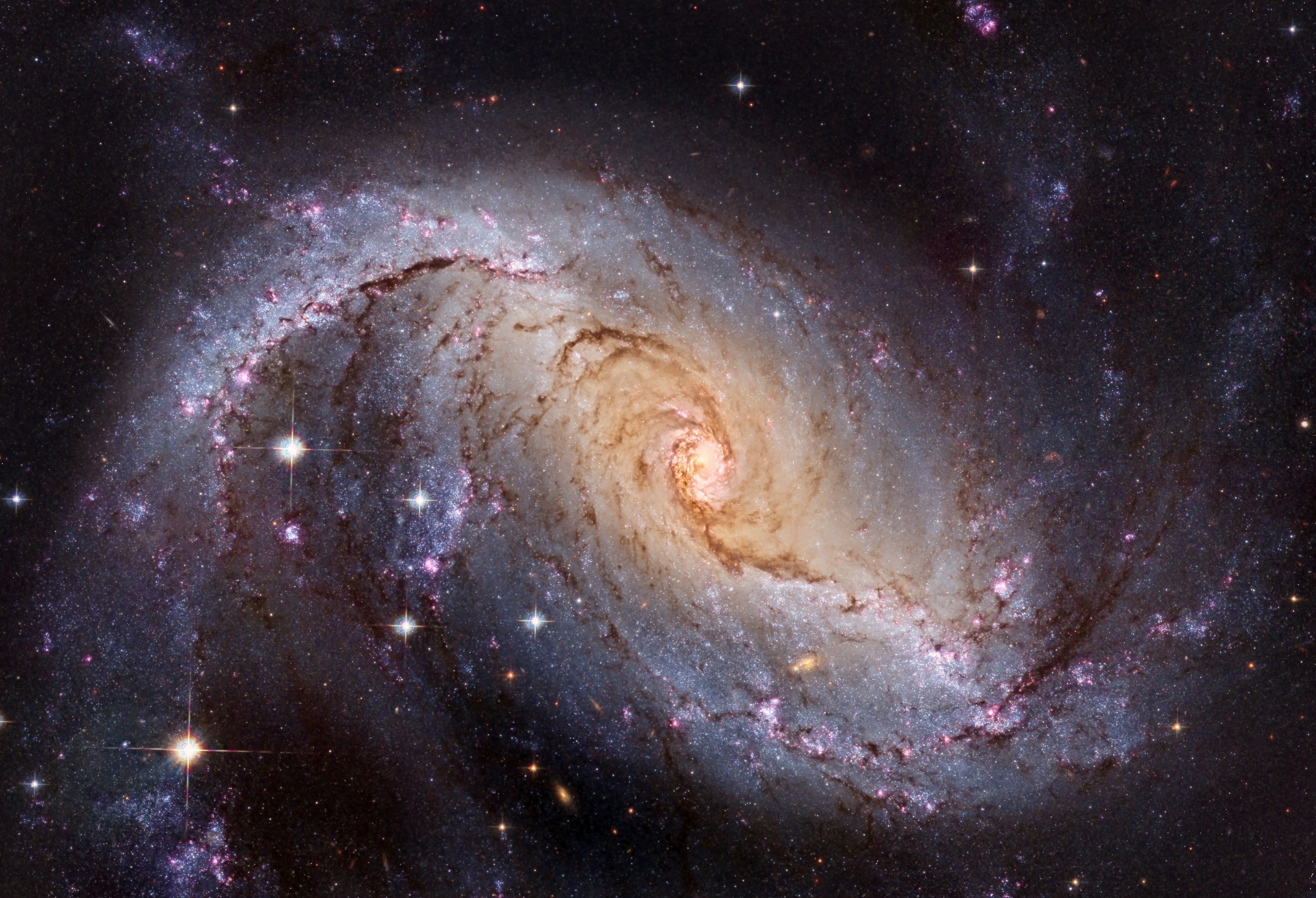 Many spiral galaxies have bars across their centers.  Even our own Milky Way Galaxy is thought to have a modest central bar. Prominently barred spiral galaxy NGC 1672, featured here, was captured in spectacular detail in an image taken by the orbiting Hubble Space Telescope. Visible are dark filamentary dust lanes, young clusters of bright blue stars, red emission nebulas of glowing hydrogen gas, a long bright bar of stars across the center, and a bright active nucleus that likely houses a supermassive black hole.  Light takes about 60 million years to reach us from NGC 1672, which spans about 75,000 light years across. NGC 1672, which appears toward the constellation of the Dolphinfish (Dorado), is being studied to find out how a spiral bar contributes to star formation in a galaxy's central regions.
