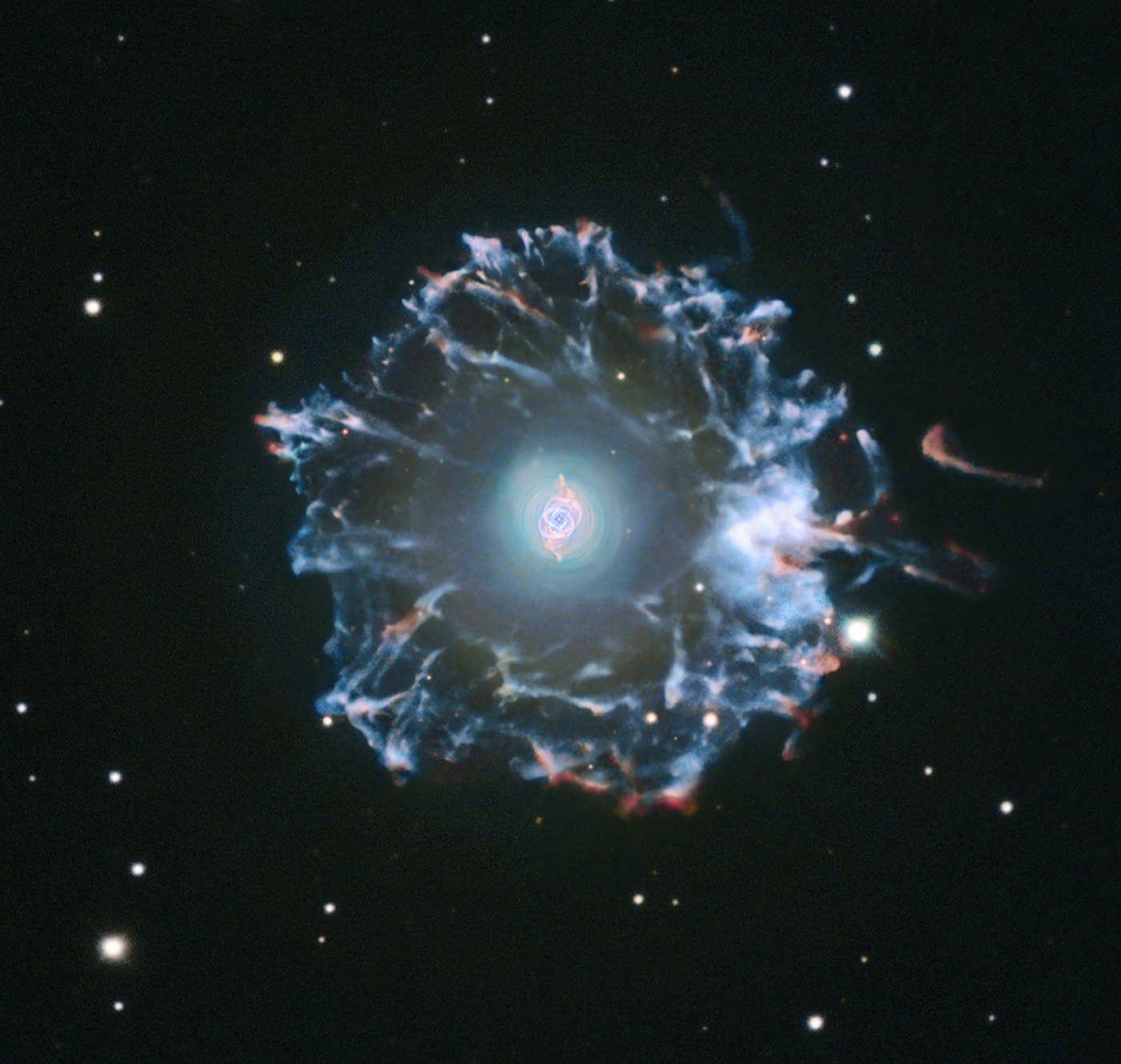 Not a Falcon 9 rocket launch after sunset, the Cat's Eye Nebula (NGC 6543) is one of the best known planetary nebulae in the sky. Its haunting symmetries are seen in the very central region of this composited picture, processed to reveal an enormous but extremely faint halo of gaseous material, over three light-years across. Made with data from ground- and space-based telescopes it shows the extended emission which surrounds the brighter, familiar planetary nebula. Planetary nebulae have long been appreciated as a final phase in the life of a sun-like star. But only more recently have some planetaries been found to have halos like this one, likely formed of material shrugged off during earlier active episodes in the star's evolution. While the planetary nebula phase is thought to last for around 10,000 years, astronomers estimate the outer filamentary portions of this halo to be 50,000 to 90,000 years old.