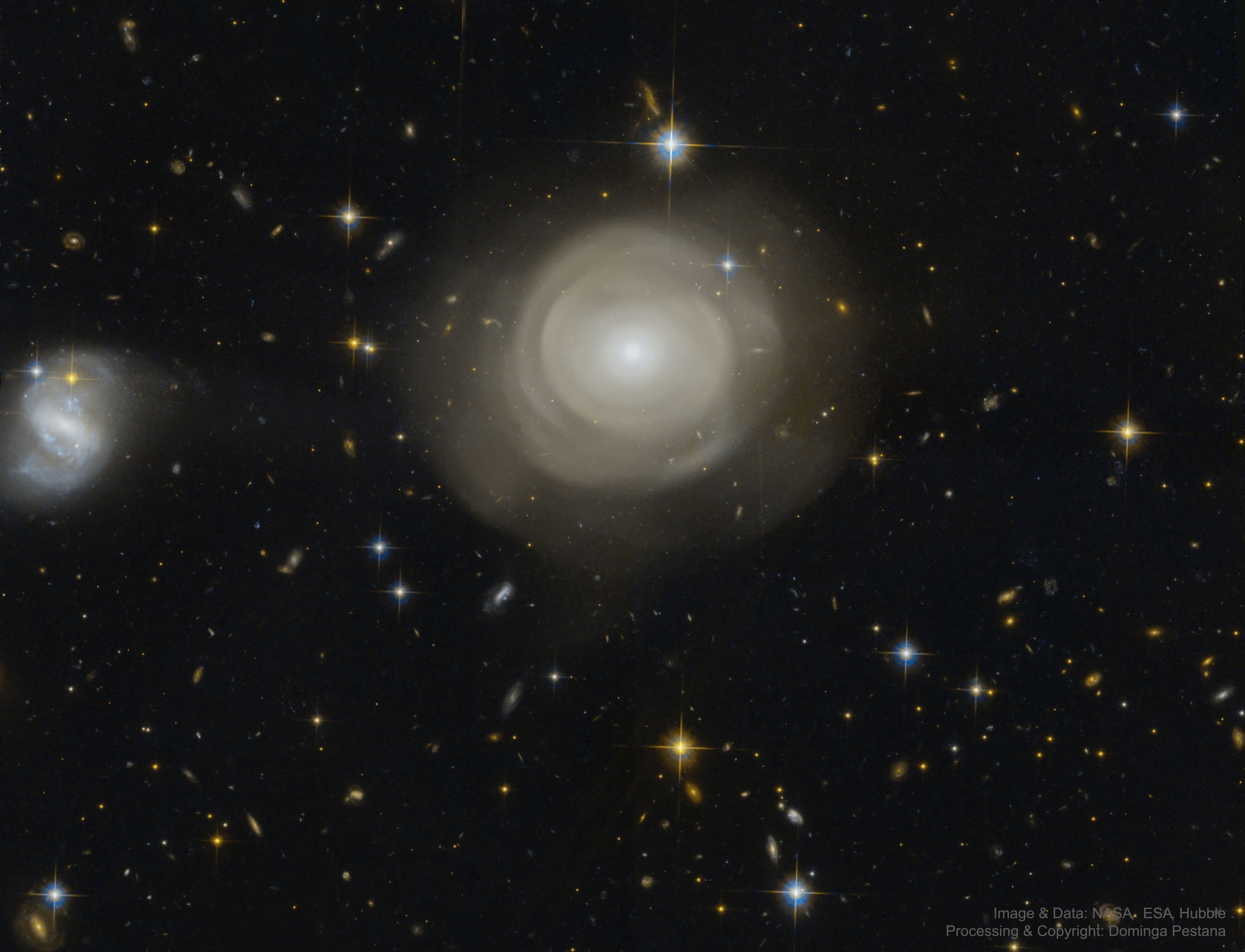 How do galaxies grow? To help find out, the Hubble Space Telescope was deployed to image the unusual elliptical galaxy PGC 42871. How this galaxy came to be surrounded by numerous shells of stars may give clues about how it evolved.  Embedded in the diffuse shells are massive globular clusters of stars -- stars which analyses show were born during three different epochs.  This and other data indicate that PGC 42871 has been in at least two galactic collisions, at least one of which might have been with a former spiral galaxy. The remaining spiral galaxy on the far left is at the same distance as PGC 42871 and may have been involved in some of the collisions.  PGC 42871 spans about 20 thousand light years and lies about 270 million light years away toward the constellation of Centaurus.    Open Science: Browse 1,800+ codes in the Astrophysics Source Code Library