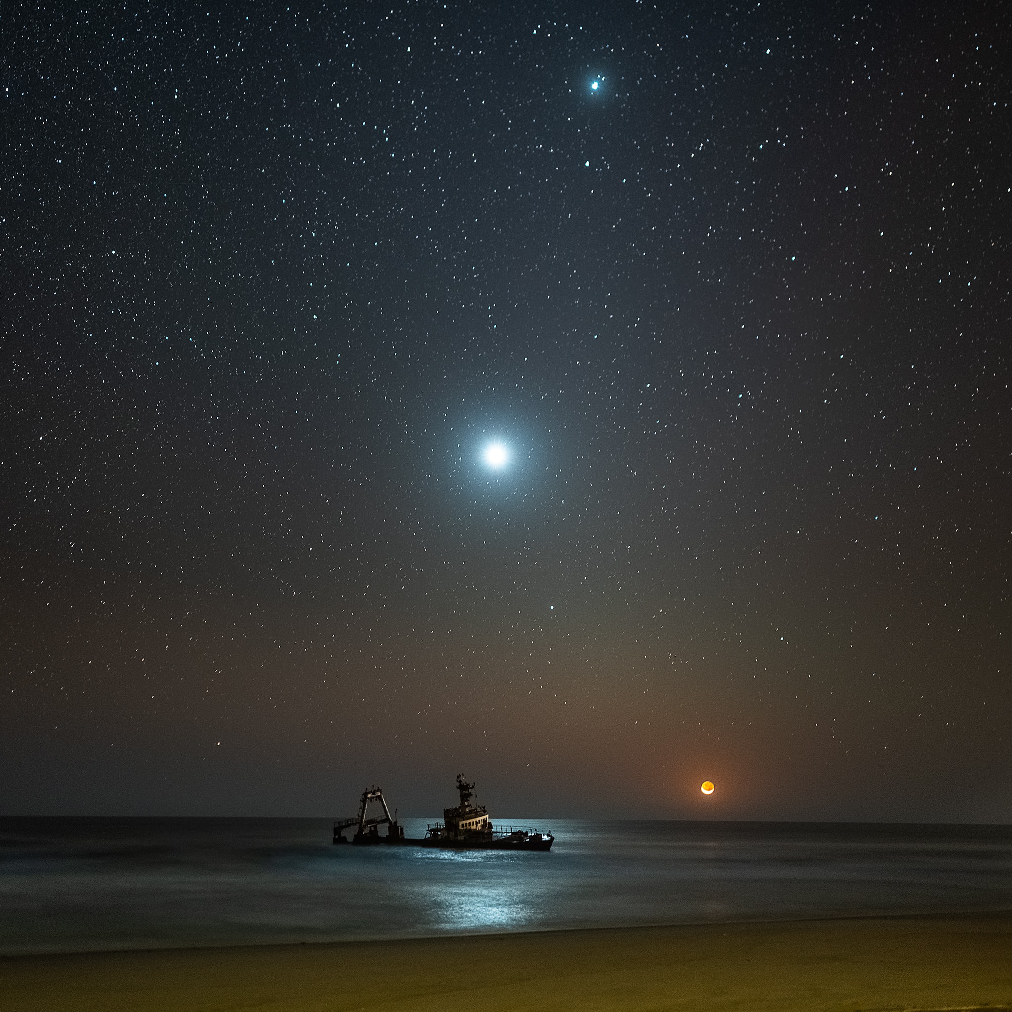 A crescent Moon is about to sink under the western horizon in this sea and night skyscape. The atmospheric photo was taken on September 11 from the desert shore along the Skeleton Coast of Namibia. So close to moonset, the moonlight is reddened and dimmed by the low, long line-of-sight across the Atlantic. But near the center of the frame Venus still shines brightly, its light reflected in calm ocean waters. The celestial beacon above the brilliant evening star is bright planet Jupiter. Namibia's Skeleton Coast was so named for the many seal and whale bones that were once strewn along the shoreline. In more recent times it's better known for shipwrecks.