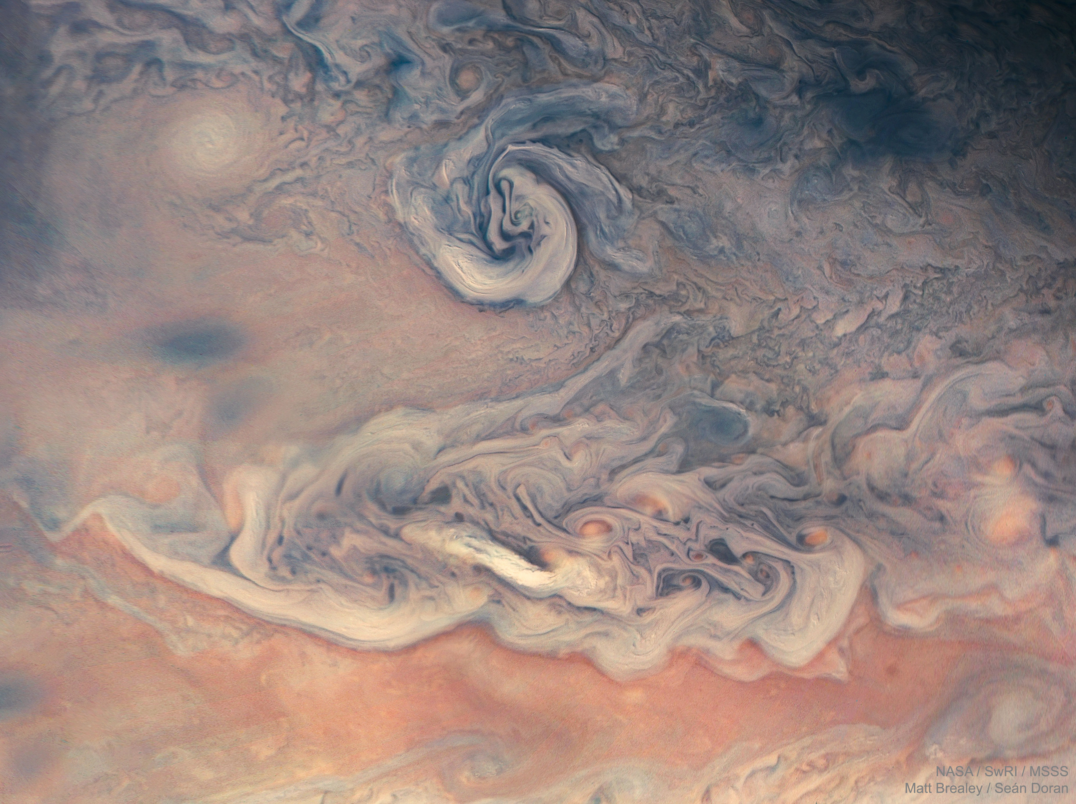 What creates the colors in Jupiter's clouds? No one is sure.  The thick atmosphere of Jupiter is mostly hydrogen and helium, elements which are colorless at the low temperatures of the Jovian cloud tops. Which trace elements provide the colors remains a topic of research, although small amounts of ammonium hydrosulfide are one leading candidate.  What is clear from the featured color-enhanced image -- and many similar images -- is that lighter clouds are typically higher up than darker ones. Pictured, light clouds swirl around reddish regions toward the lower right, while they appear to cover over some darker domains on the upper right. The featured image was taken by the robotic Juno spacecraft during its 14th low pass over Jupiter earlier this year.  Juno continues in its looping elliptical orbit, swooping near the huge planet every 53 days and exploring a slightly different sector each time around.