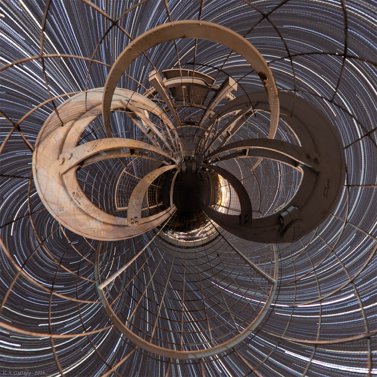Don't panic. This little planet projection looks confusing, but it's actually just a digitally warped and stitched, nadir centered mosaic of images that covers nearly 360x180 degrees. The images were taken on the night of October 31 from a 30 meter tall hill-top lookout tower near Tatabanya, Hungary, planet Earth. The laticed lookout tower construction was converted from a local mine elevator. Since planet Earth is rotating, the 126 frames of 75 second long exposures also show warped, concentric star trails with the north celestial pole at the left. Of course at this location the south celestial pole is just right of center but below the the little planet's horizon.