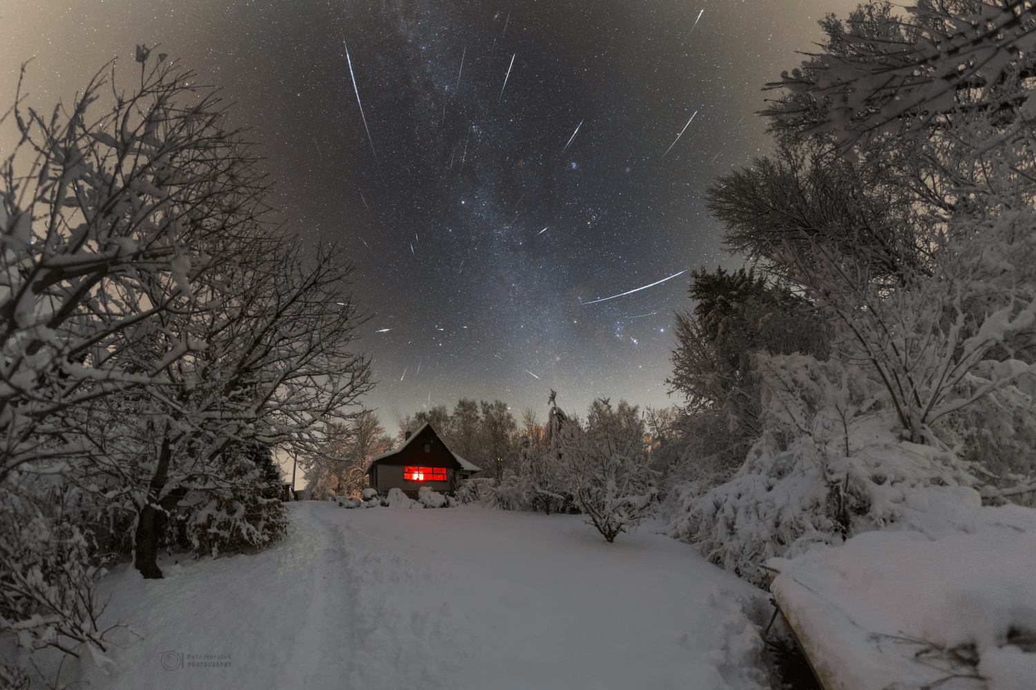 They say Orion always comes up sideways, and he does seem to on this cold December night. The bright stars of the familiar northern winter constellation lie just above the snowy tree tops surrounding a cozy cottage near the town of Ustupky in the Czech Republic. But Gemini's meteors also seem to rain on the wintry landscape. The meteor streaks are captured in exposures made near last Friday's peak of the annual Geminid meteor shower. They stream away from the shower's radiant above the trees, near the two bright stars of the zodiacal constellation of the Twins. Comet Wirtanen, a visitor to planet Earth's skies, is visible too. Look for its telltale greenish coma near the stars of the seven sisters.