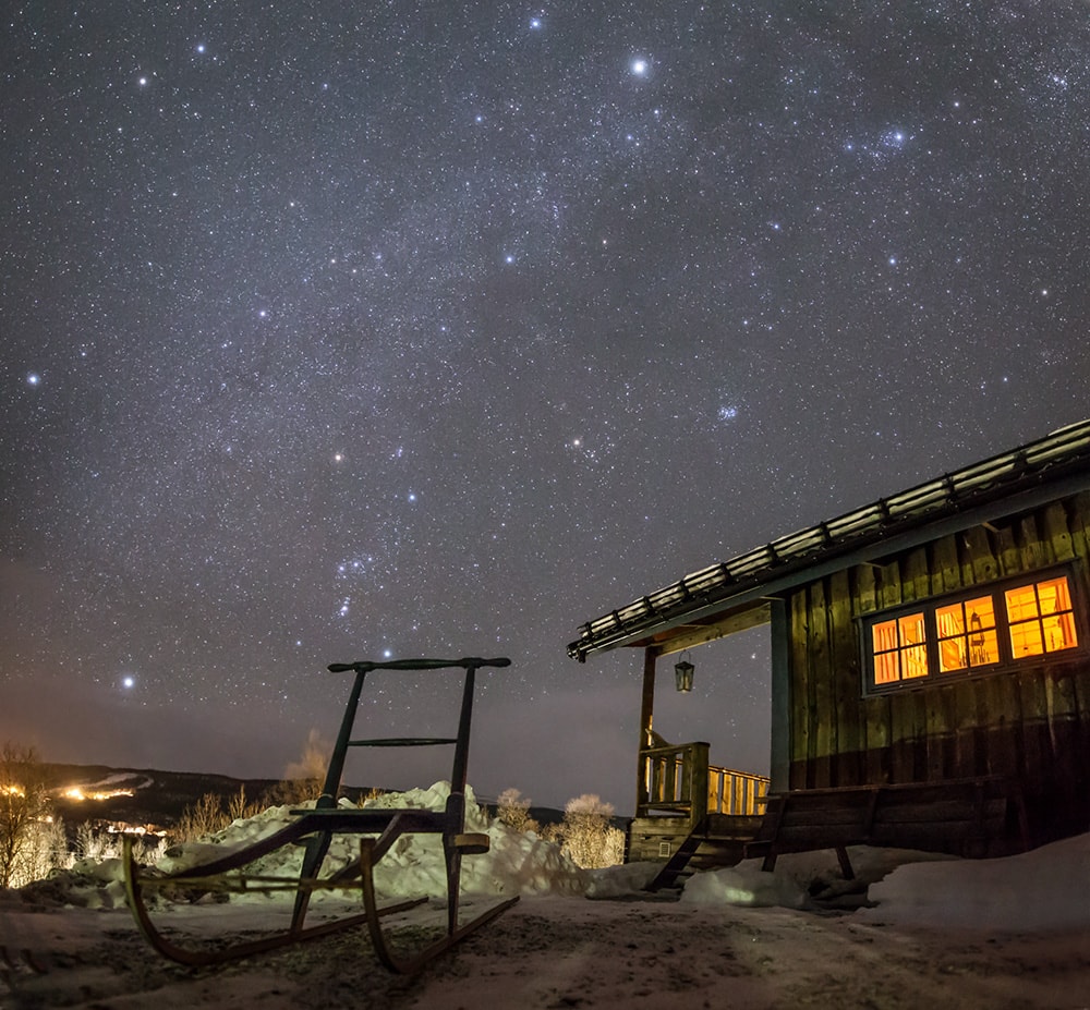Gocka's, a family nickname for the mountain cabin, and a wooden sled from a generation past stand quietly under the stars. The single exposure image was taken on January 6 from Tanndalen Sweden to evoke a simple visual experience of the dark mountain skies. A pale band of starlight along the Milky Way sweeps through the scene. At the foot of Orion the Hunter, bright star Rigel shines just above the old kicksled's handrail. Capella, alpha star of Auriga the celestial charioteer, is the brightest star at the top of the frame. In fact, the familiar stars of the winter hexagon and the Pleiades star cluster can all be found in this beautiful skyscape from a northern winter night.