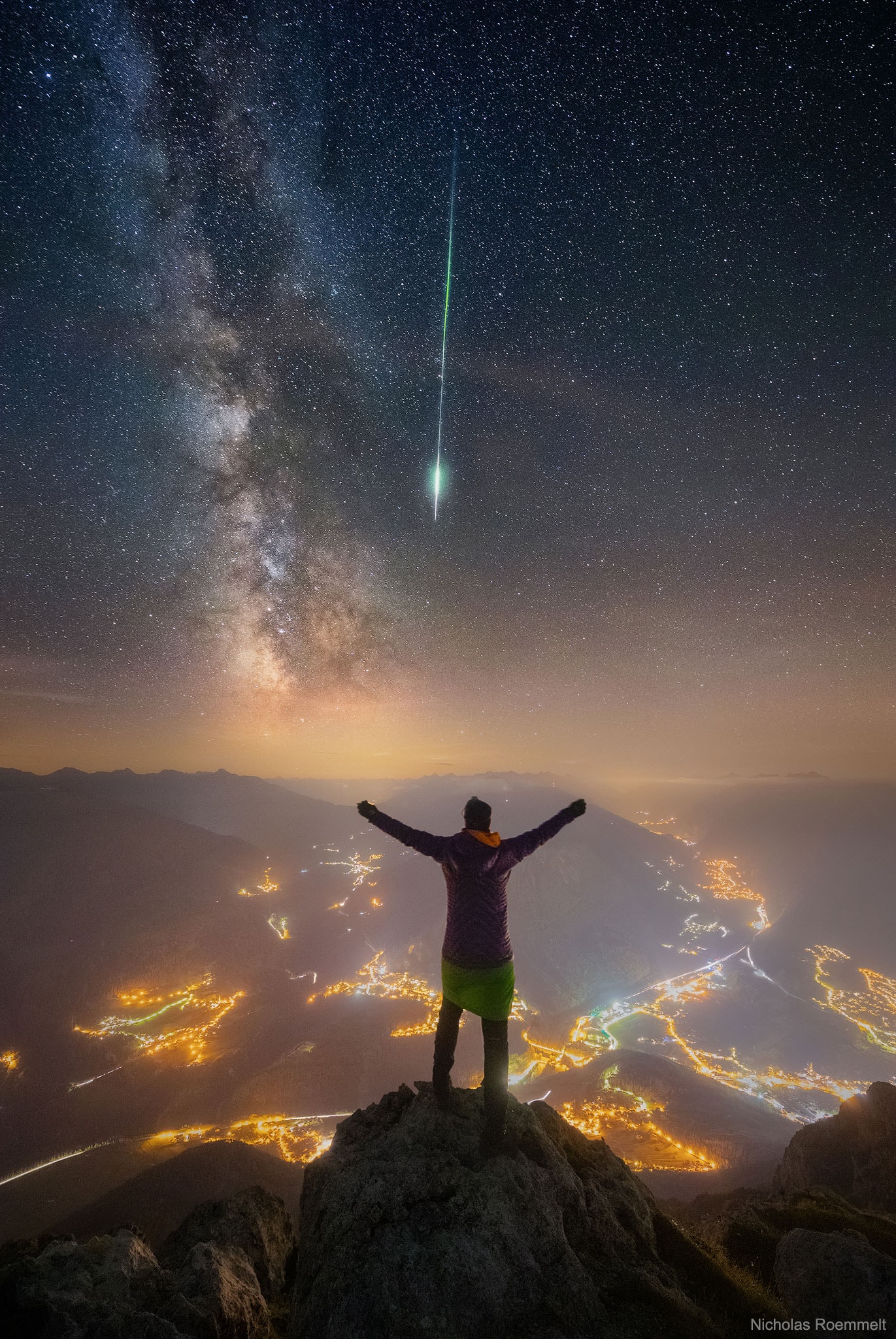 Now this was a view with a thrill. From Mount Tschirgant in the Alps, you can see not only nearby towns and distant Tyrolean peaks, but also, weather permitting, stars, nebulas, and the band of the Milky Way Galaxy. What made the arduous climb worthwhile this night, though, was another peak -- the peak of the 2018 Perseids Meteor Shower. As hoped, dispersing clouds allowed a picturesque sky-gazing session that included many faint meteors, all while a carefully positioned camera took a series of exposures. Suddenly, a thrilling meteor -- bright and colorful -- slashed down right next the nearly vertical band of the Milky Way.  As luck would have it, the camera caught it too.  Therefore, a new image in the series was quickly taken with one of the sky-gazers posing on the nearby peak. Later, all of the images were digitally combined.
