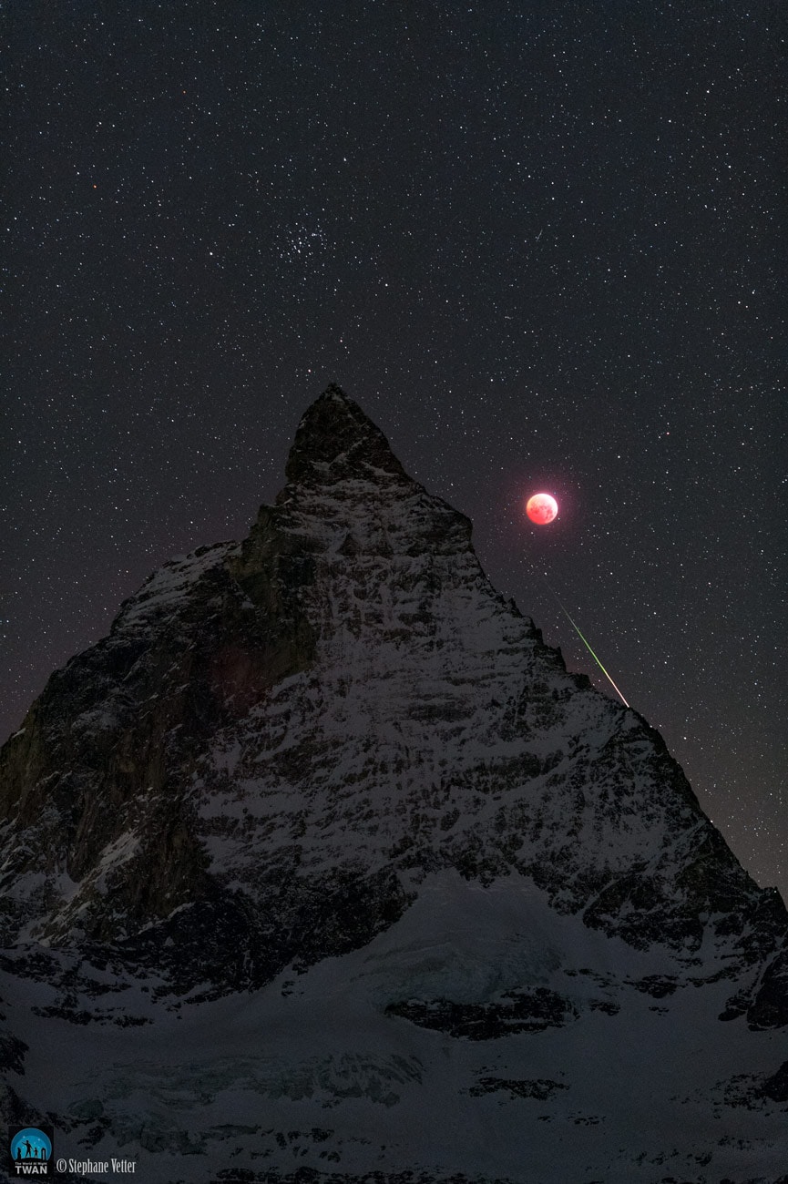 Fans of planet Earth probably recognize the Matterhorn in the foreground of this night skyscape. Famed in mountaineering history, the 4,478 meter Alpine mountain stands next to the totally eclipsed Moon. In spite of -22 degree C temperatures, the inspired scene was captured on the morning of January 21 from the mountains near Zermatt, Switzerland. Different exposures record the dim red light reflected by the Moon fully immersed in Earth's shadow. Seen directly above the famous Alpine peak, but about 600 light-years away, are the stars of the Praesepe or Beehive star cluster also known as Messier 44. An added reward to the cold eclipse vigil, a bright and colorful meteor flashed below the temporarily dimmmed Moon, just tracing the Matterhorn's north-eastern climbing route along Hornli ridge.