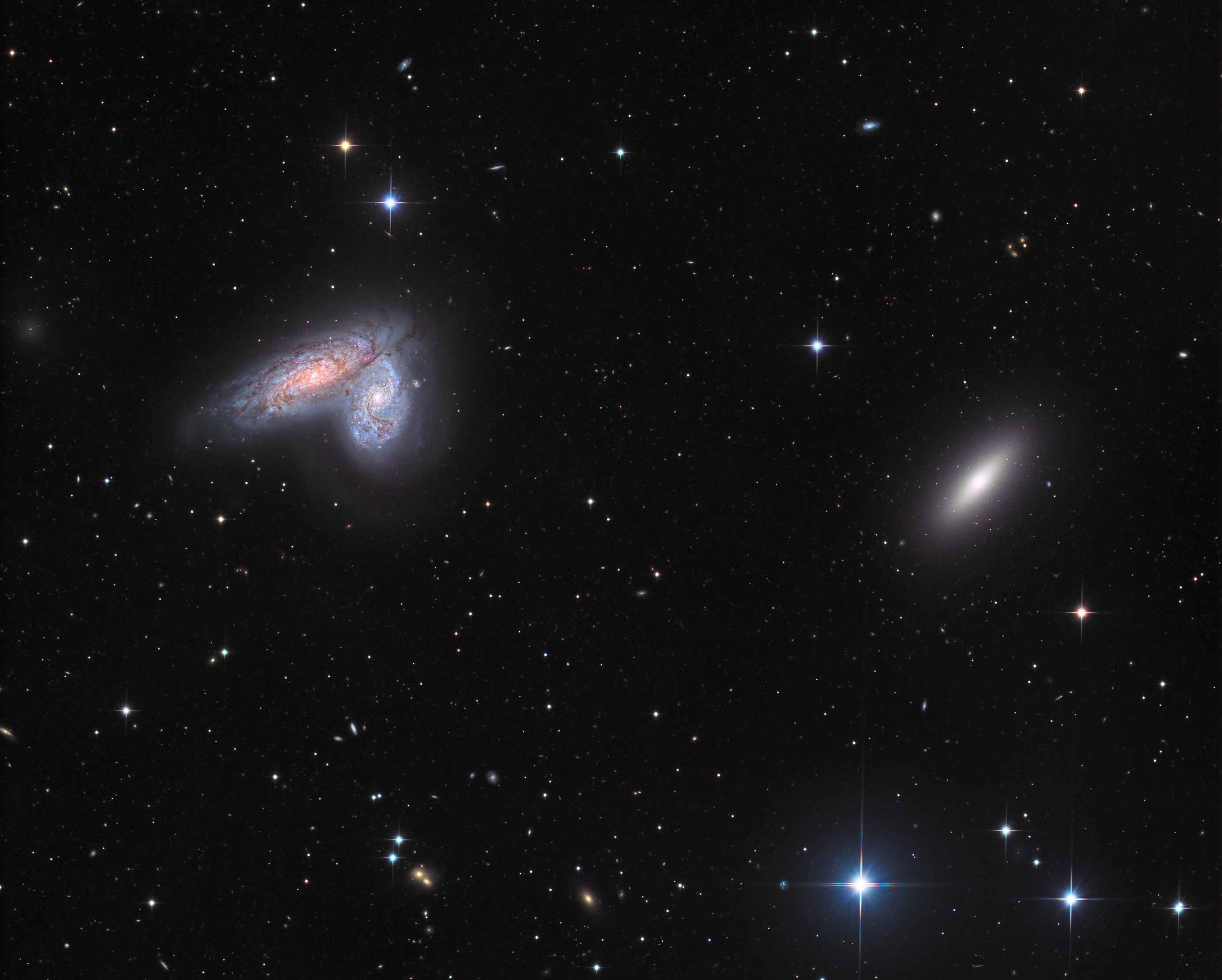 Spiral galaxy pair NGC 4567 and NGC 4568 share this sharp cosmic vista with lonely elliptical galaxy NGC 4564. All are members of the large Virgo Galaxy Cluster. With their classic spiral arms, dust lanes, and star clusters, the eye-catching spiral pair is also known as the Butterfly Galaxies. Very close together, the galaxy twins don't seem to be too distorted by gravitational tides. Their giant molecular clouds are known to be colliding though and are likely fueling the formation of massive star clusters. The galaxy twins are about 52 million light-years distant, while their bright cores appear separated by about 20,000 light-years. Of course, the spiky foreground stars lie within our own Milky Way.
