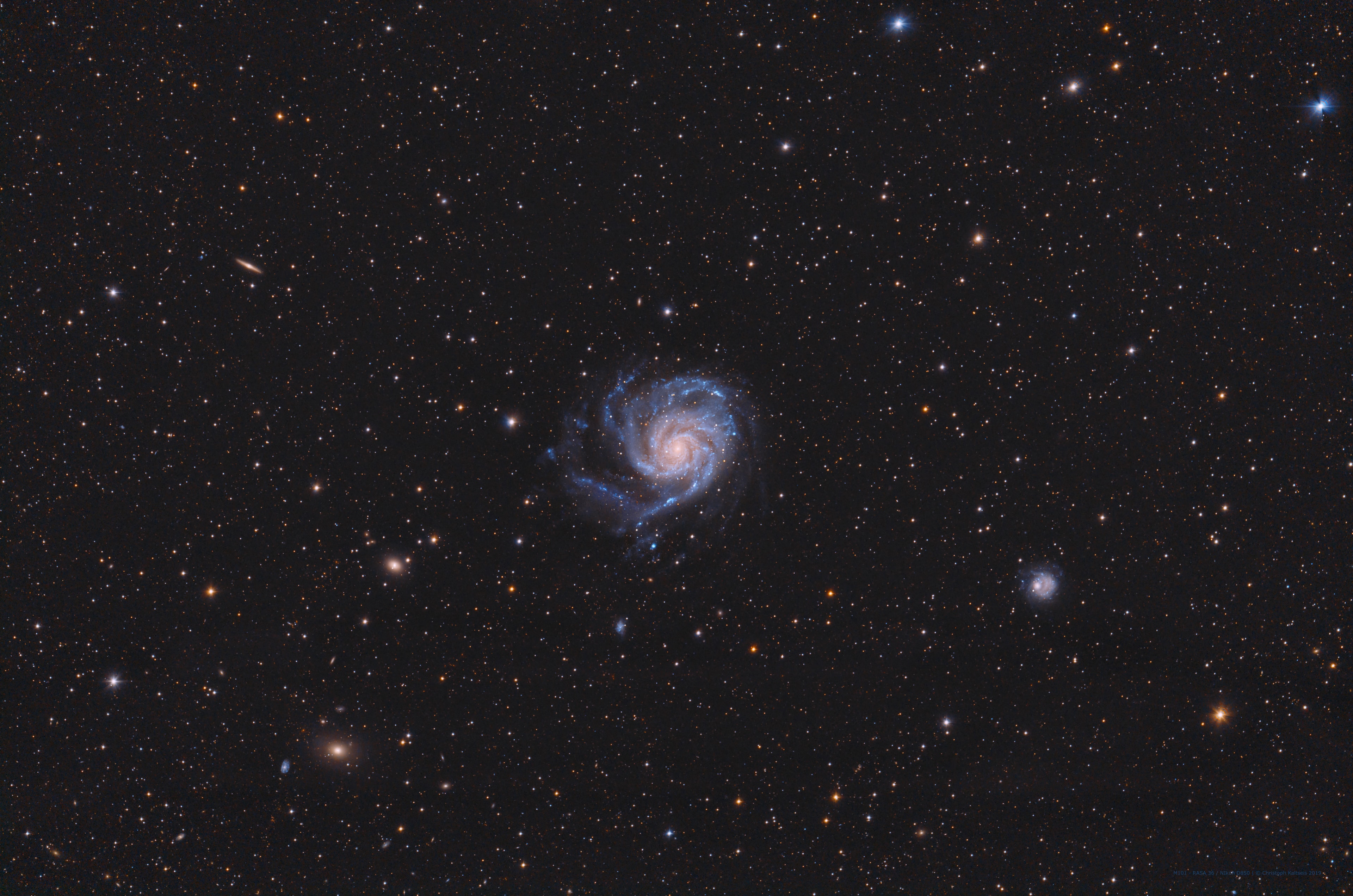 Big, beautiful spiral galaxy M101 is one of the last entries in Charles Messier's famous catalog, but definitely not one of the least. About 170,000 light-years across, this galaxy is enormous, almost twice the size of our own Milky Way galaxy. M101 was also one of the original spiral nebulae observed by Lord Rosse's large 19th century telescope, the Leviathan of Parsontown. M101 shares this modern telescopic field of view with more distant background galaxies, foreground stars within the Milky Way, and a companion dwarf galaxy NGC 5474 (lower right). The colors of the Milky Way stars can also be found in the starlight from the large island universe. Its core is dominated by light from cool yellowish stars. Along its grand design spiral arms are the blue colors of hotter, young stars mixed with obscuring dust lanes and pinkish star forming regions. Also known as the Pinwheel Galaxy, M101 lies within the boundaries of the northern constellation Ursa Major, about 23 million light-years away. Its companion NGC 5474 has likely been distorted by its past gravitational interactions with the dominant M101.