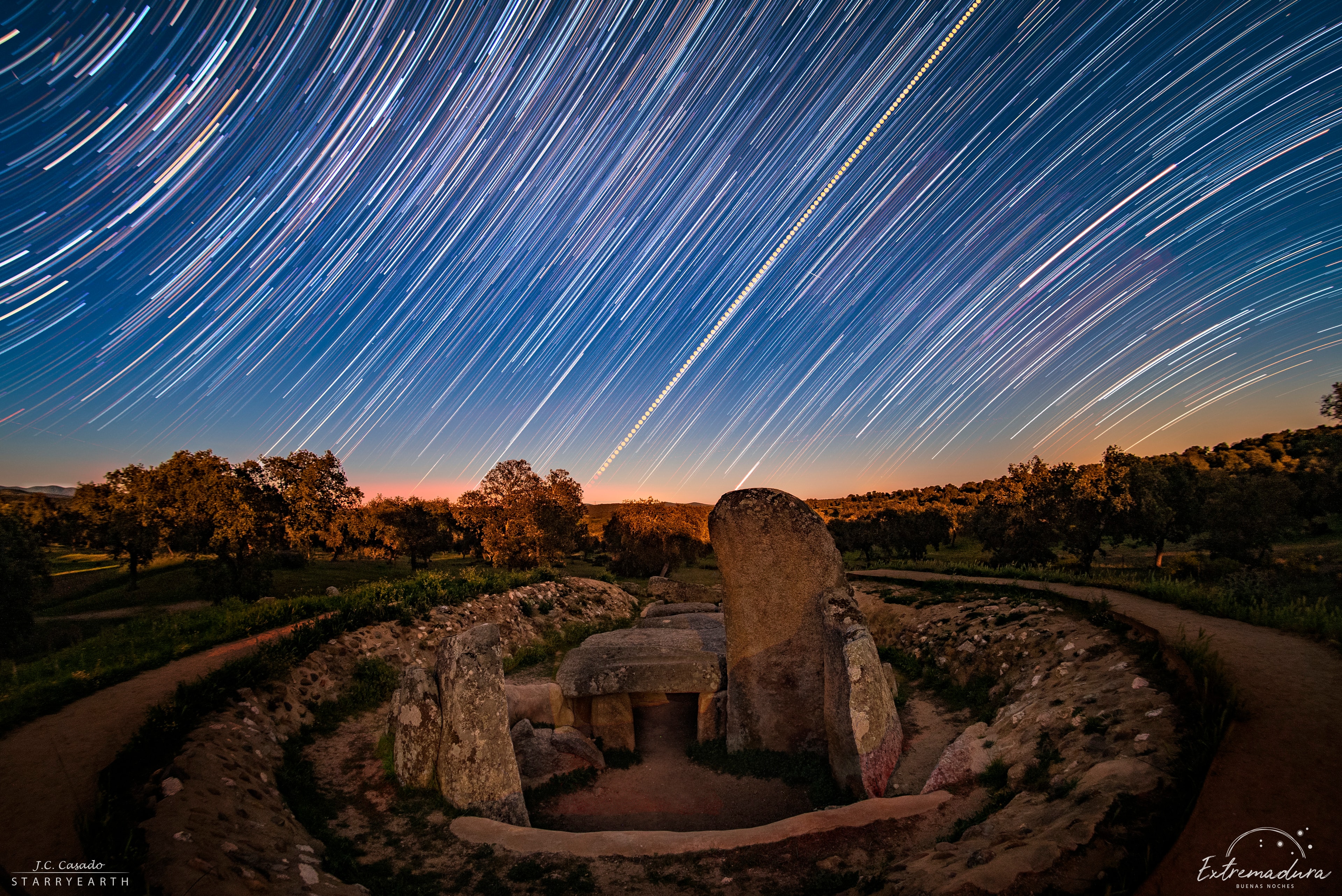 Stars trail and the Sun rises in this night and day composite panorama made on March 19. The view looks toward the eastern horizon from La Nava de Santiago, Spain. To create it, a continuous series of digital frames was recorded for about two hours and combined to trace the concentric motion of the stars through the night sky. A reflection of the Earth's rotation, star trails curve around the north celestial pole toward upper left and the south celestial pole toward the lower right. Of course on that day the Sun was near the celestial equator, a diagonal straight line in the wide-angle projection. A dense dimming filter was used to capture the Sun's image every two minutes. Superimposed on the star trails it rose due east in the morning sky. In the scene, foreground landscape and a local prehistoric monument were illuminated by full moonlight, though. The monument's corridor faces nearly to the east and the equinox sunrise.