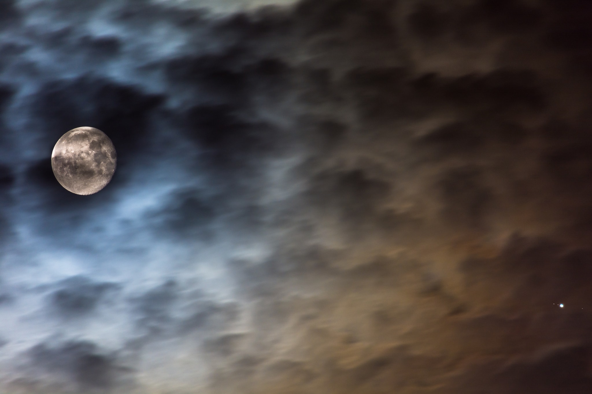 On May 20, a nearly Full Moon and Jupiter shared this telephoto field of view. Captured when a passing cloud bank dimmed the moonlight, the single exposure reveals the familiar face of our fair planet's own large natural satellite, along with bright Jupiter (lower right) and some of its Galilean moons. Lined up left to right the tiny pinpricks of light near Jupiter are Ganymede, Europa, [Jupiter] and Callisto. (That's not just dust on your screen ...) Closer and brighter, our own natural satellite appears to loom large. But Ganymede, and Callisto are physically larger than Earth's Moon, while water world Europa is only slightly smaller.  In fact, of the Solar System's six largest planetary satellites, Saturn's moon Titan is missing from the scene and a fourth Galilean moon, Io, is hidden by our ruling gas giant.