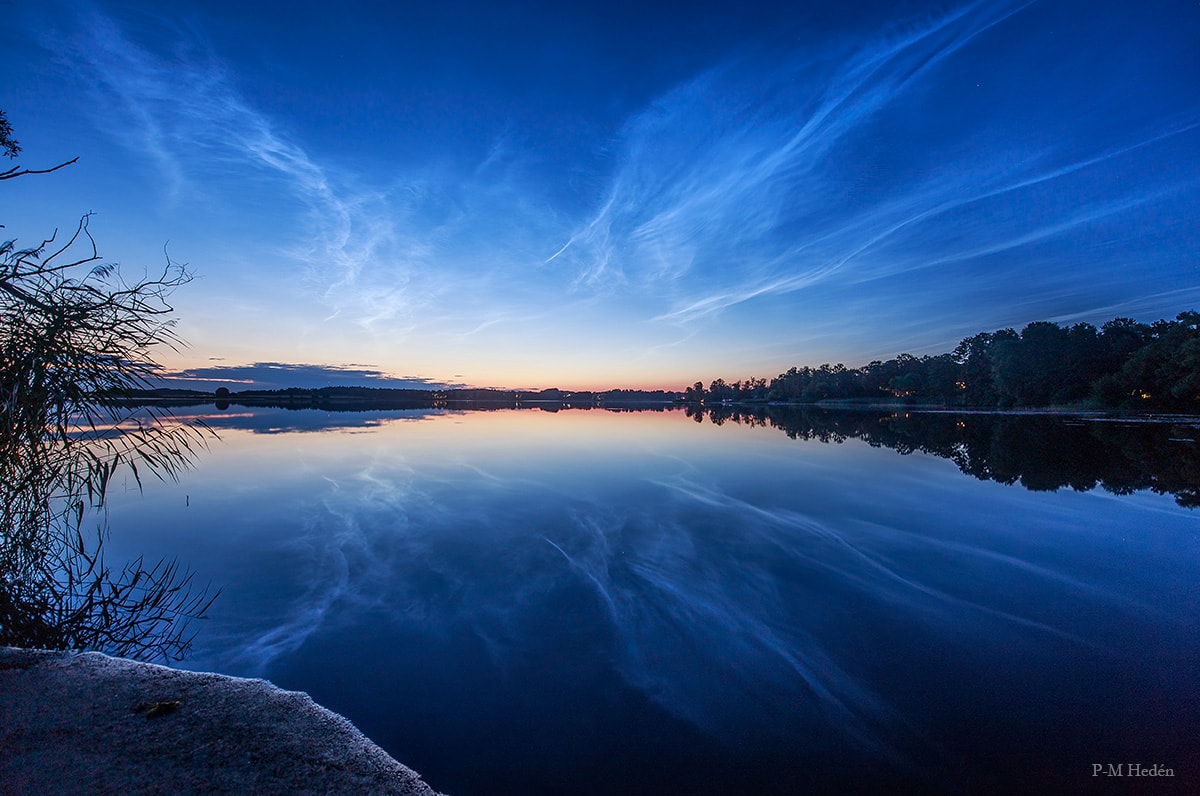 Transfusing sunlight through a still dark sky, this exceptional display of noctilucent clouds was captured earlier this month, reflected in the calm waters of Vallentuna Lake near Stockholm, Sweden. From the edge of space, about 80 kilometers above Earth's surface, the icy clouds themselves still reflect sunlight even though the Sun is below the horizon as seen from the ground. Usually spotted at high latitudes in summer months the night shining clouds have made a strong showing so far during the short northern summer nights. Also known as polar mesopheric clouds they are understood to form as water vapor driven into the cold upper atmosphere condenses on the fine dust particles supplied by disintegrating meteors or volcanic ash. NASA's AIM mission provides daily projections of noctilucent clouds as seen from space.