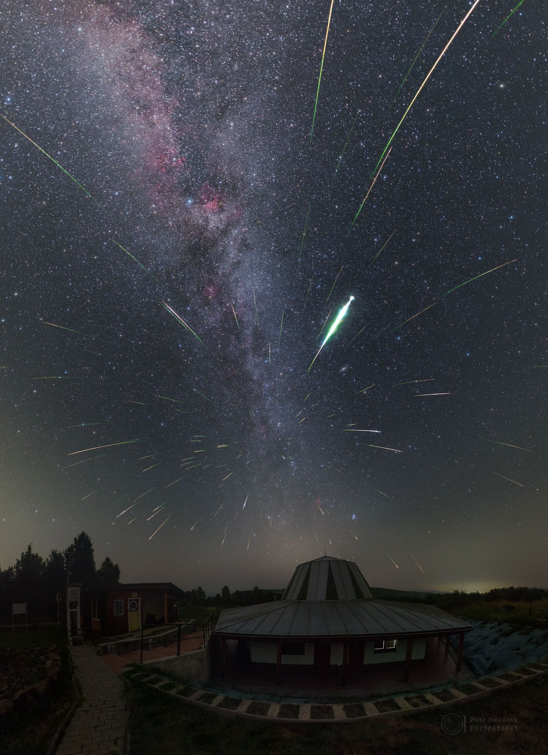 Tonight is a good night to see meteors.  Comet dust will rain down on planet Earth, streaking through dark skies during the peak of the annual Perseid Meteor Shower.  The featured composite image was taken during last year's Perseids from the Poloniny Dark Sky Park in Slovakia.  The unusual building in the foreground is a planetarium on the grounds of Kolonica Observatory. Although the comet dust particles travel parallel to each other, the resulting shower meteors clearly seem to radiate from a single point on the sky in the eponymous constellation Perseus.  The radiant effect is due to perspective, as the parallel tracks appear to converge at a distance, like train tracks.  The Perseid Meteor Shower is expected to peak after midnight tonight, although unfortunately this year the sky will be brightened by a near full Moon.