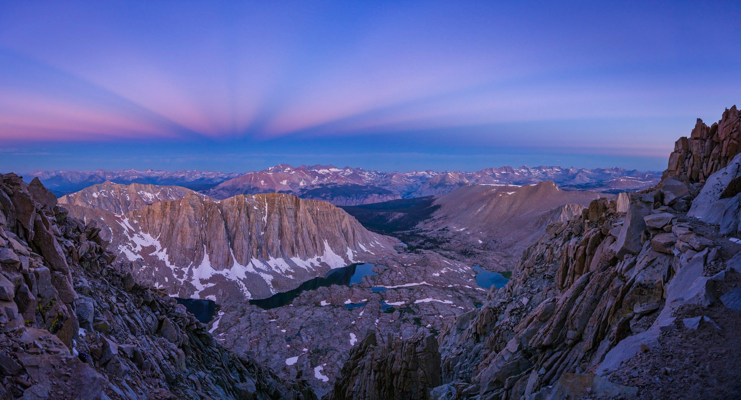 Nature photographers and other fans of planet Earth always look forward to the blue hour. That's the transition in twilight, just before sunrise or after sunset, when the Sun is below the horizon but land and sky are still suffused with beautiful bluish hues of light. On August 8 this early morning blue hour panorama scanned along the clear western sky, away from the impending sunrise. A breathtaking scene, it looks down the slopes of Mt. Whitney, from along the John Muir Trail toward rugged peaks of planet Earth's Sierra Nevada mountain range. Above the horizon a faint pinkish band of back scattered sunlight, the anti-twilight arch or Belt of Venus, borders the falling grey shadow of Earth itself. Subtle bands of light across the clear sky are anti-crepuscular rays, defined by shadows of clouds near the sunward horizon. Actually following parallel lines they seem to converge along the horizon at the point opposite the rising Sun due to perspective.