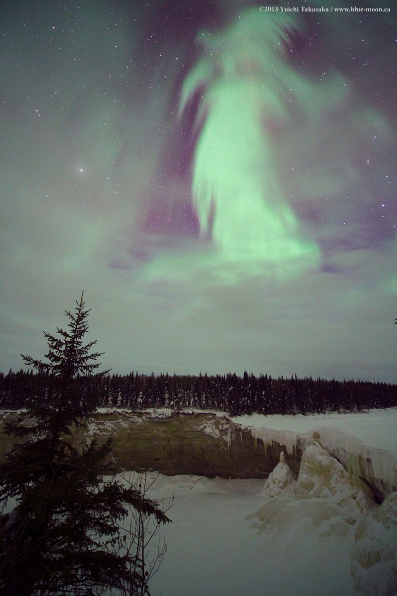 What does this aurora look like to you? While braving the cold to watch the skies above northern Canada early one morning in 2013, a most unusual aurora appeared.  The aurora definitely appeared to be shaped like something , but what? Two ghostly possibilities recorded by the astrophotographer were "witch" and "goddess of dawn", but please feel free to suggest your own Halloween-enhanced impressions. Regardless of fantastical pareidolic interpretations, the pictured aurora had a typical green color and was surely caused by the scientifically commonplace action of high energy particles from space interacting with oxygen in Earth's upper atmosphere.  In the image foreground, at the bottom, is a frozen Alexandra Falls, while evergreen trees cross the middle.