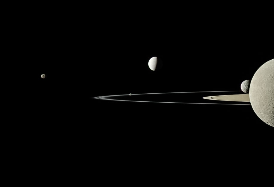 On July 29, 2011 the Cassini spacecraft's narrow-angle camera took this snapshot and captured 5 of Saturn's moons, from just above the ringplane. Left to right are small moons Janus and Pandora respectively 179 and 81 kilometers across, shiny 504 kilometer diameter Enceladus, and Mimas, 396 kilometers across, seen just next to Rhea. Cut off by the right edge of the frame, Rhea is Saturn's second largest moon at 1,528 kilometers across. So how many moons does Saturn have? Twenty new found outer satellites bring its total to 82 known moons, and since Jupiter's moon total stands at 79, Saturn is the Solar System's new moon king. The newly announced Saturnian satellites are all very small, 5 kilometers or so in diameter, and most are in retrograde orbits inclined to Saturn's ringplane. You can help name Saturn's new moons, but you should understand the rules. Hint: A knowledge of Norse, Inuit, and Gallic mythology will help.