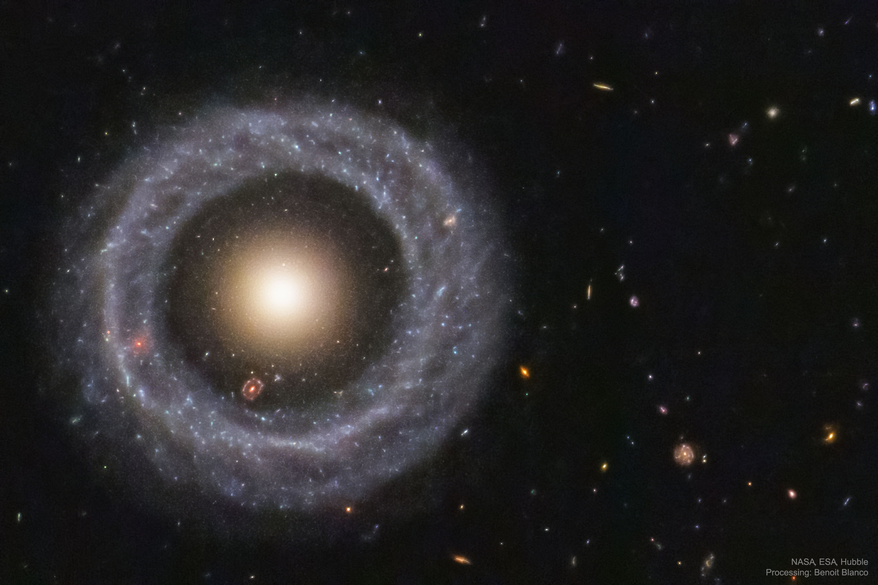 Is this one galaxy or two?  This question came to light in 1950 when astronomer Arthur Hoag chanced upon this unusual extragalactic object.  On the outside is a ring dominated by bright blue stars, while near the center lies a ball of much redder stars that are likely much older.  Between the two is a gap that appears almost completely dark.  How Hoag's Object formed, including its nearly perfectly round ring of stars and gas, remains unknown.  Genesis hypotheses include a galaxy collision billions of years ago and the gravitational effect of a central bar that has since vanished. The featured photo was taken by the Hubble Space Telescope and recently reprocessed using an artificially intelligent de-noising algorithm.  Observations in radio waves indicate that Hoag's Object has not accreted a smaller galaxy in the past billion years.  Hoag's Object spans about 100,000 light years and lies about 600 million light years away toward the constellation of the Snake (Serpens).  Many galaxies far in the distance are visible toward the right, while coincidentally, visible in the gap at about seven o'clock, is another but more distant ring galaxy.