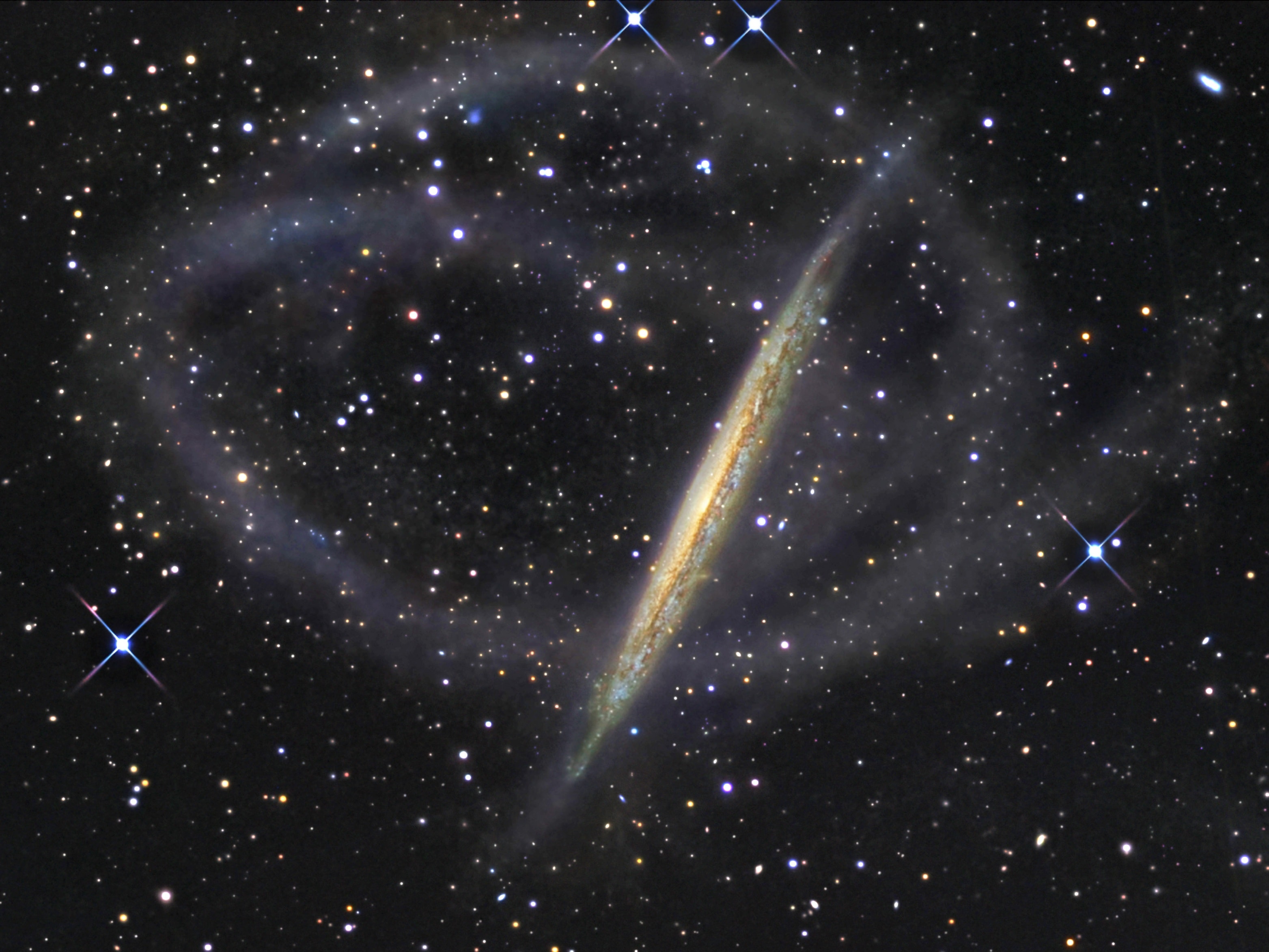 Grand tidal streams of stars seem to surround galaxy NGC 5907. The arcing structures form tenuous loops extending more than 150,000 light-years from the narrow, edge-on spiral, also known as the Splinter or Knife Edge Galaxy. Recorded only in very deep exposures, the streams likely represent the ghostly trail of a dwarf galaxy - debris left along the orbit of a smaller satellite galaxy that was gradually torn apart and merged with NGC 5907 over four billion years ago. Ultimately this remarkable discovery image, from a small robotic observatory in New Mexico, supports the cosmological scenario in which large spiral galaxies, including our own Milky Way, were formed by the accretion of smaller ones. NGC 5907 lies about 40 million light-years distant in the northern constellation Draco.