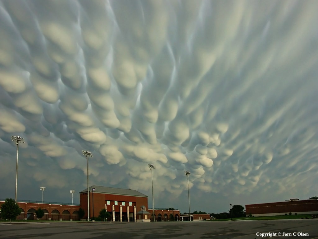 When do cloud bottoms appear like bubbles? Normally, cloud bottoms are flat. This is because moist warm air that rises and cools will condense into water droplets at a specific temperature, which usually corresponds to a very specific height.  As water droplets grow, an opaque cloud forms.  Under some conditions, however, cloud pockets can develop that contain large droplets of water or ice that fall into clear air as they evaporate.  Such pockets may occur in turbulent air near a thunderstorm.  Resulting mammatus clouds can appear especially dramatic if sunlit from the side.  The mammatus clouds pictured here were photographed over Hastings, Nebraska during 2004 June.