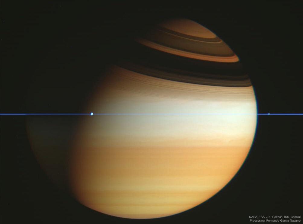 If this is Saturn, where are the rings?  When Saturn's "appendages" disappeared in 1612, Galileo did not understand why.   Later that century, it became understood that Saturn's unusual protrusions were rings and that when the Earth crosses the ring plane, the edge-on rings will appear to disappear.  This is because Saturn's rings are confined to a plane many times thinner, in proportion, than a razor blade.  In modern times, the robot Cassini spacecraft orbiting Saturn frequently crossed Saturn's ring plane during its mission to Saturn, from 2004 to 2017.  A series of plane crossing images from 2005 February was dug out of the vast online Cassini raw image archive by interested Spanish amateur Fernando Garcia Navarro.  Pictured here, digitally cropped and set in representative colors, is the striking result.  Saturn's thin ring plane appears in blue, bands and clouds in Saturn's upper atmosphere appear in gold. Details of Saturn's rings can be seen in the high dark shadows across the top of this image, taken back in 2005. The moons Dione and Enceladus appear as bumps in the rings.    Free Presentation: APOD Editor to show best astronomy images of 2019 -- and the decade -- in NYC on January 3