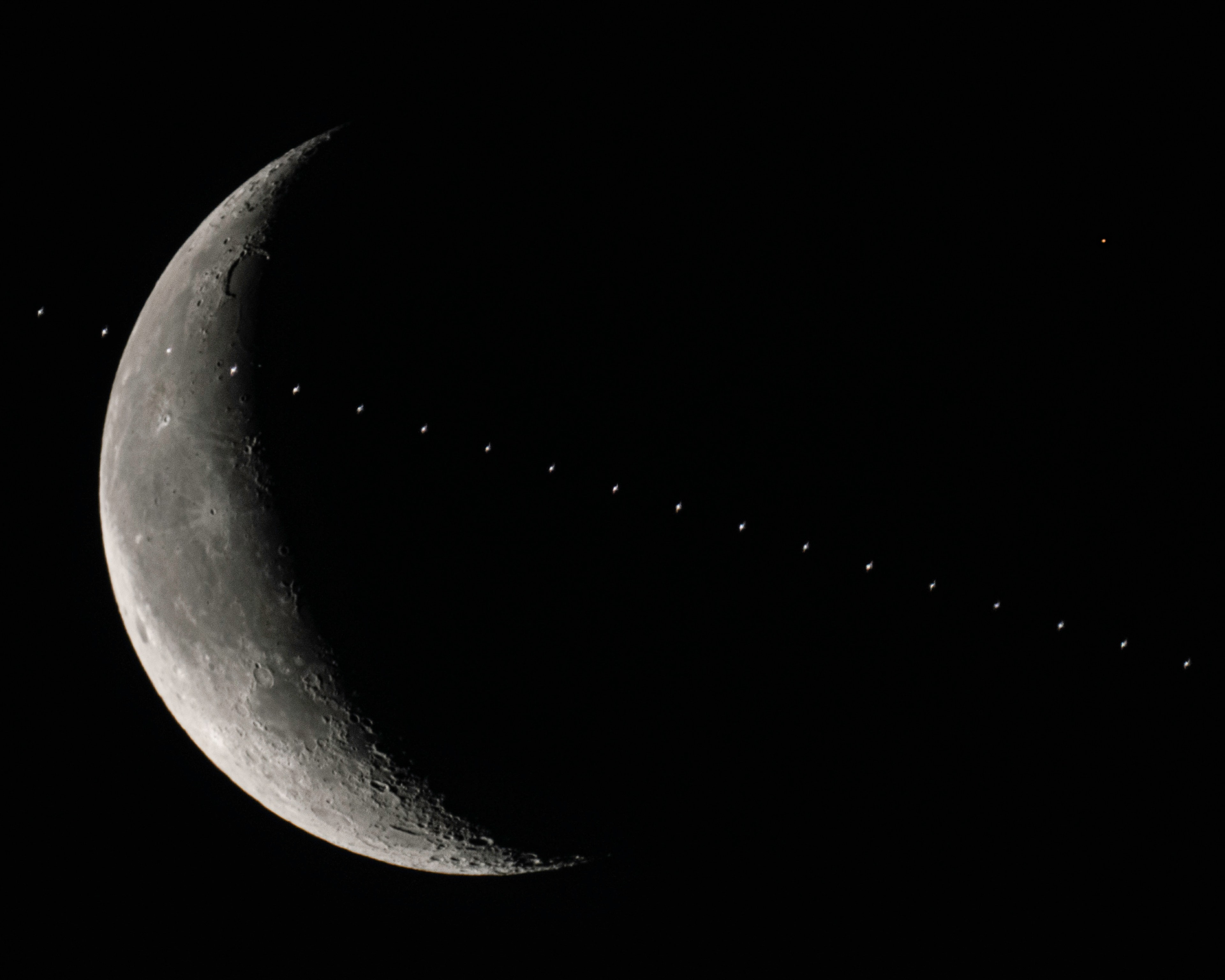 On February 18, as civil twilight began in northern New Mexico skies, the International Space Station, a waning crescent Moon, and planet Mars for a moment shared this well-planned single field of view. From the photographer's location the sky had just begun to grow light, but the space station orbiting 400 kilometers above the Earth was already bathed in the morning sunlight. At 6:25am local time it took about a second to cross in front of the lunar disk moving right to left in the composited successive frames. At the time, Mars itself had already emerged from behind the Moon following its much anticipated lunar occultation. The yellowish glow of the Red Planet is still in the frame at the upper right, beyond the Moon's dark edge.