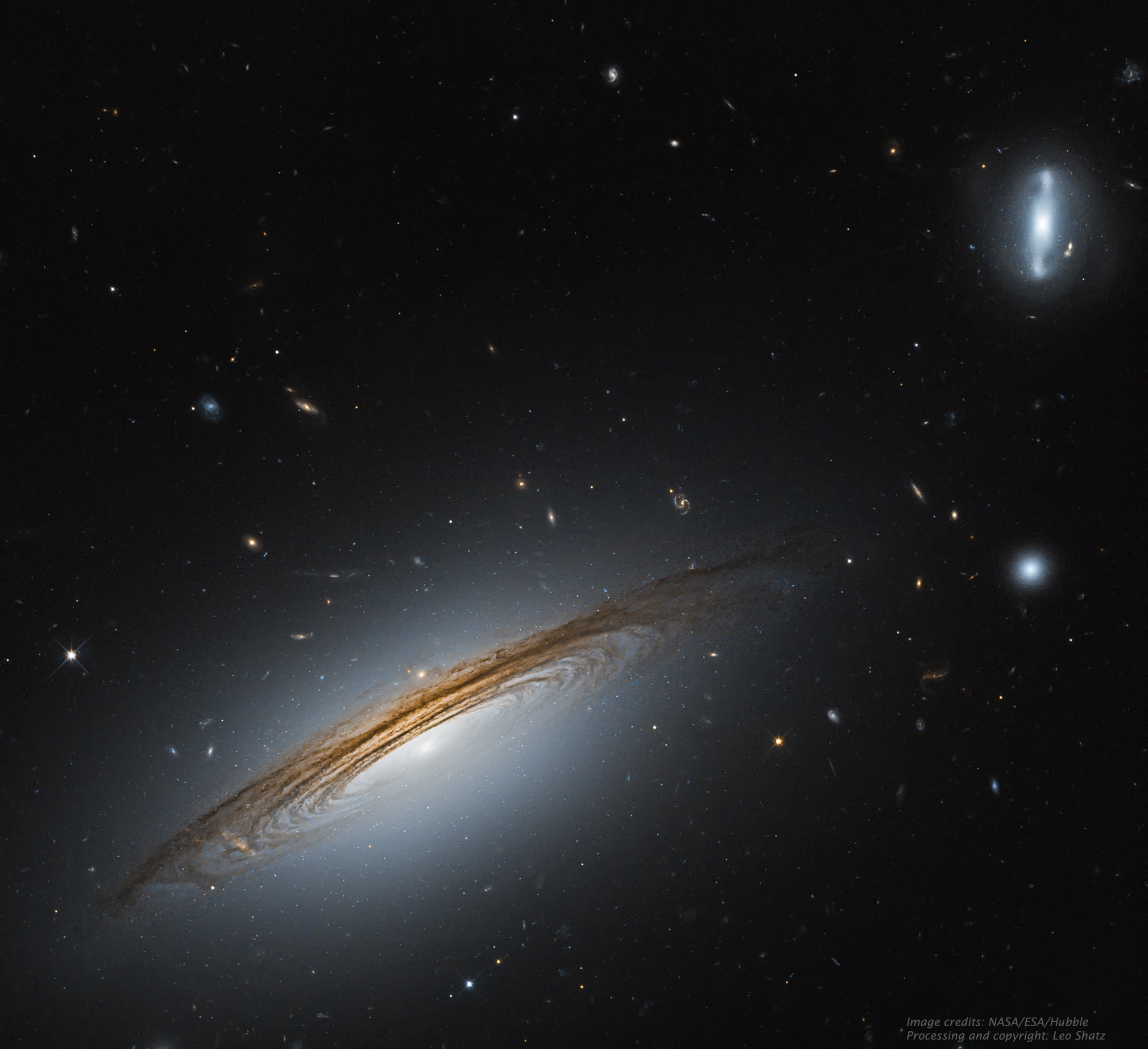 Why does this galaxy spin so fast?  To start, even identifying which type of galaxy UGC 12591 is difficult -- featured on the lower left, it has dark dust lanes like a spiral galaxy but a large diffuse bulge of stars like a lenticular. Surprisingly observations show that UGC 12591 spins at about 480 km/sec, almost twice as fast as our Milky Way, and the fastest rotation rate yet measured.  The mass needed to hold together a galaxy spinning this fast is several times the mass of our Milky Way Galaxy. Progenitor scenarios for UGC 12591 include slow growth by accreting ambient matter, or rapid growth through a recent galaxy collision or collisions -- future observations may tell.  The light we see today from UGC 12591 left about 400 million years ago, when trees were first developing on Earth.